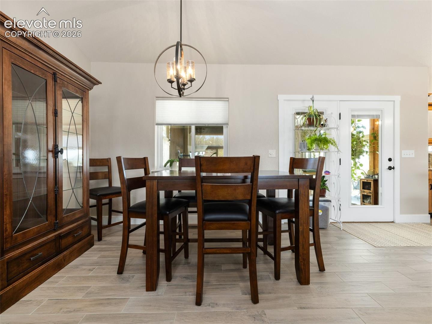 Wood-finish flooring, built-in display cabinetry, double French doors, and a decorative ceiling light fixture