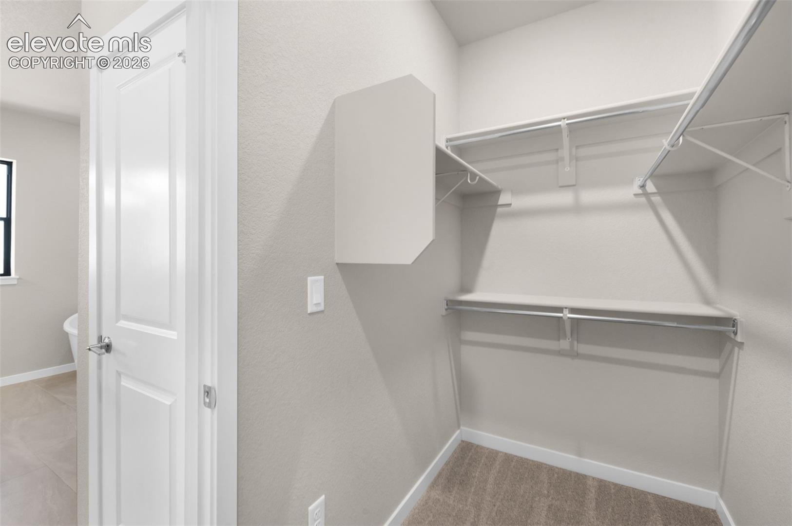 Walk-in closet with wire shelving, integrated hanging rods, and neutral carpet