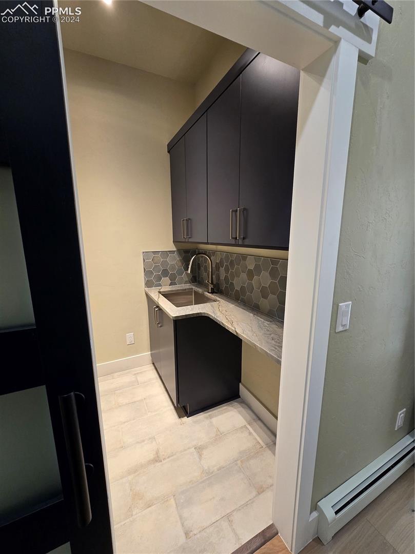 Laundry room featuring a baseboard heating unit, sink, and decorative backsplash