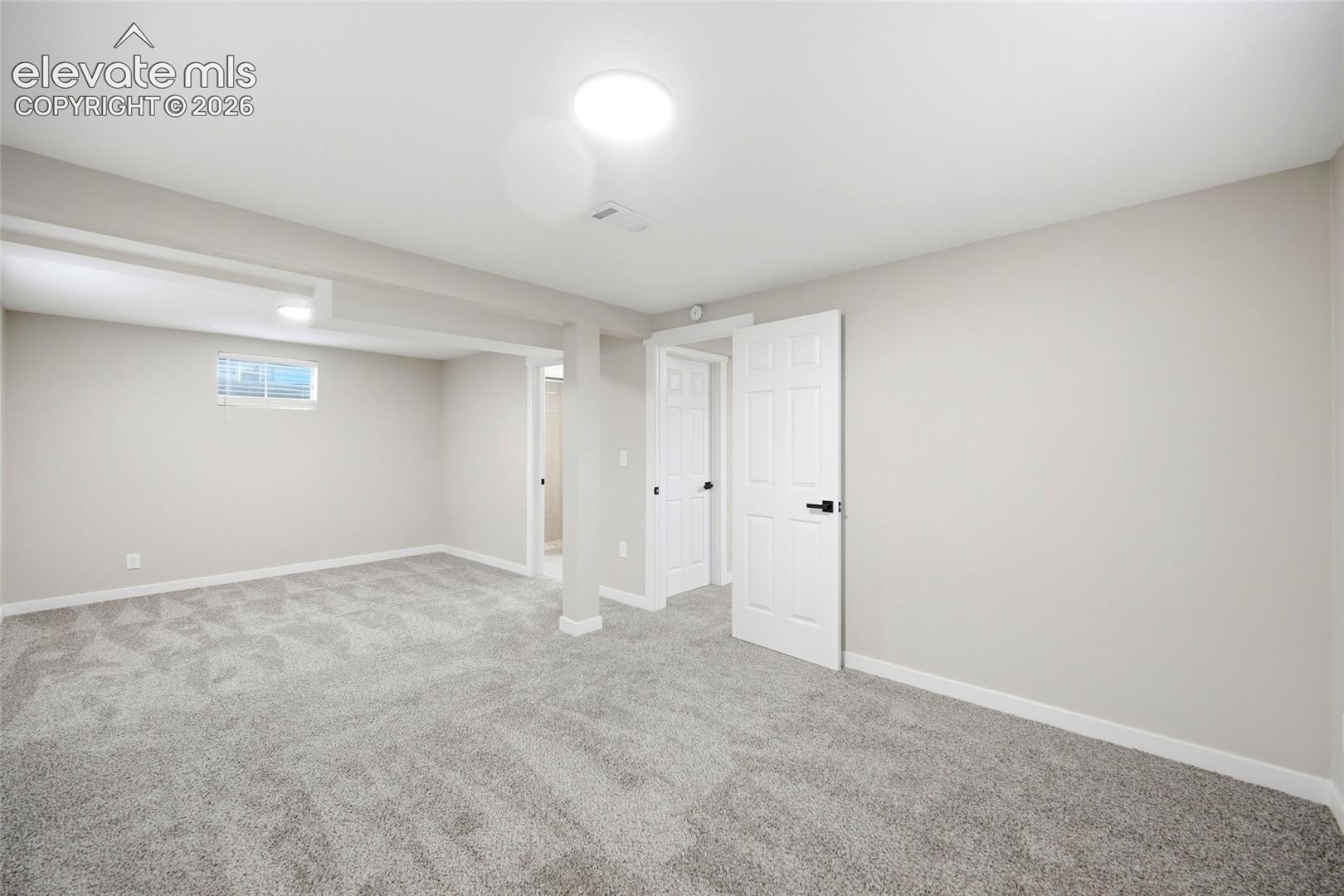 Expansive carpeted area with neutral wall finishes, recessed lighting, and white paneled doors
