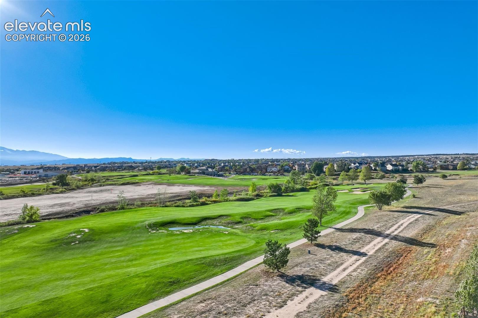 Expansive golf course setting featuring manicured greens and a paved cart path