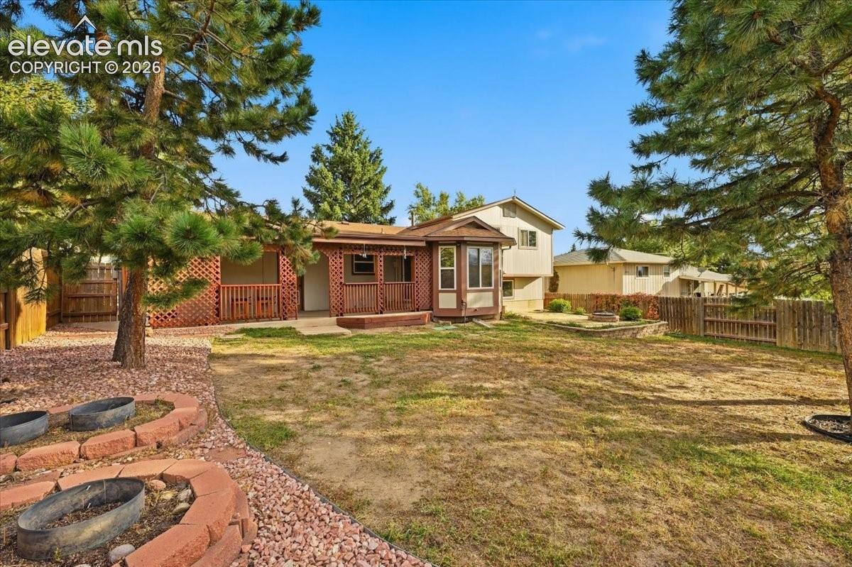 Expansive backyard featuring a patio, a built-in fire pit, and mature trees