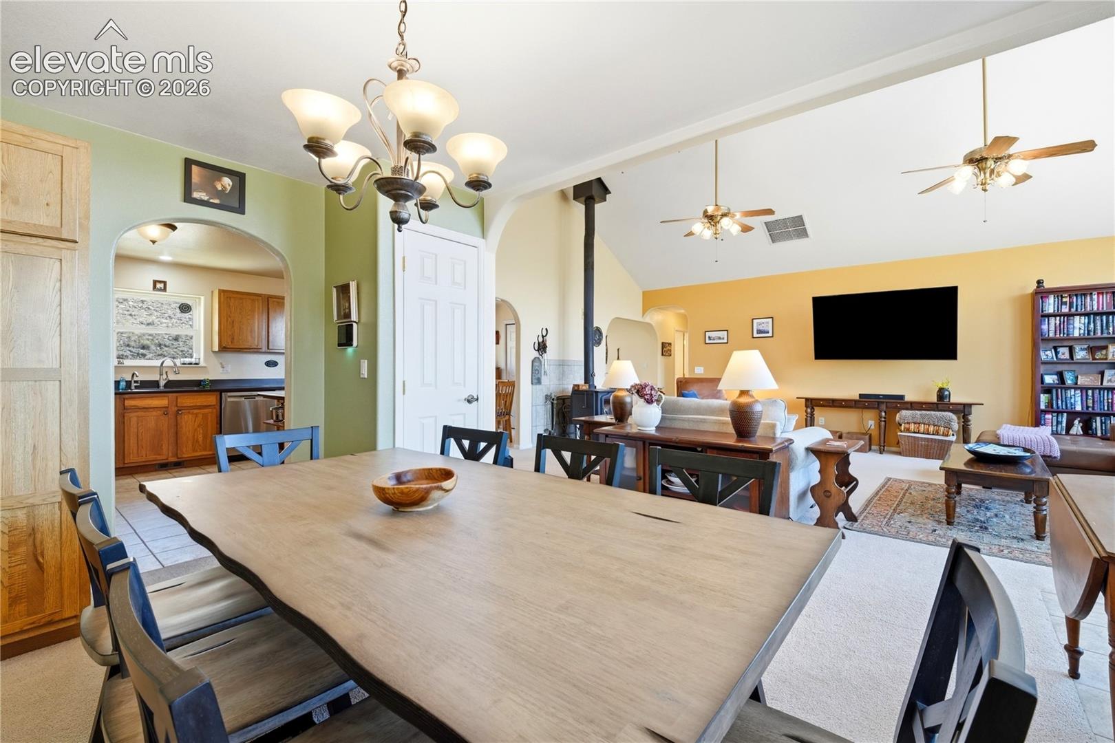 Vaulted ceilings, archway entries, and a multi-light chandelier enhance the living space