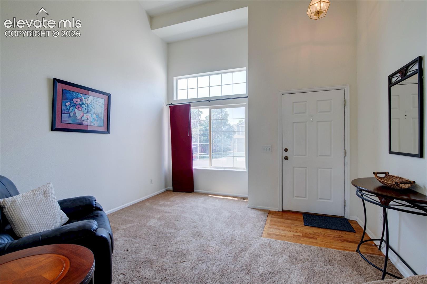 Entry area with vaulted ceiling, large windows, transom window, recessed entryway, and wood-finish flooring