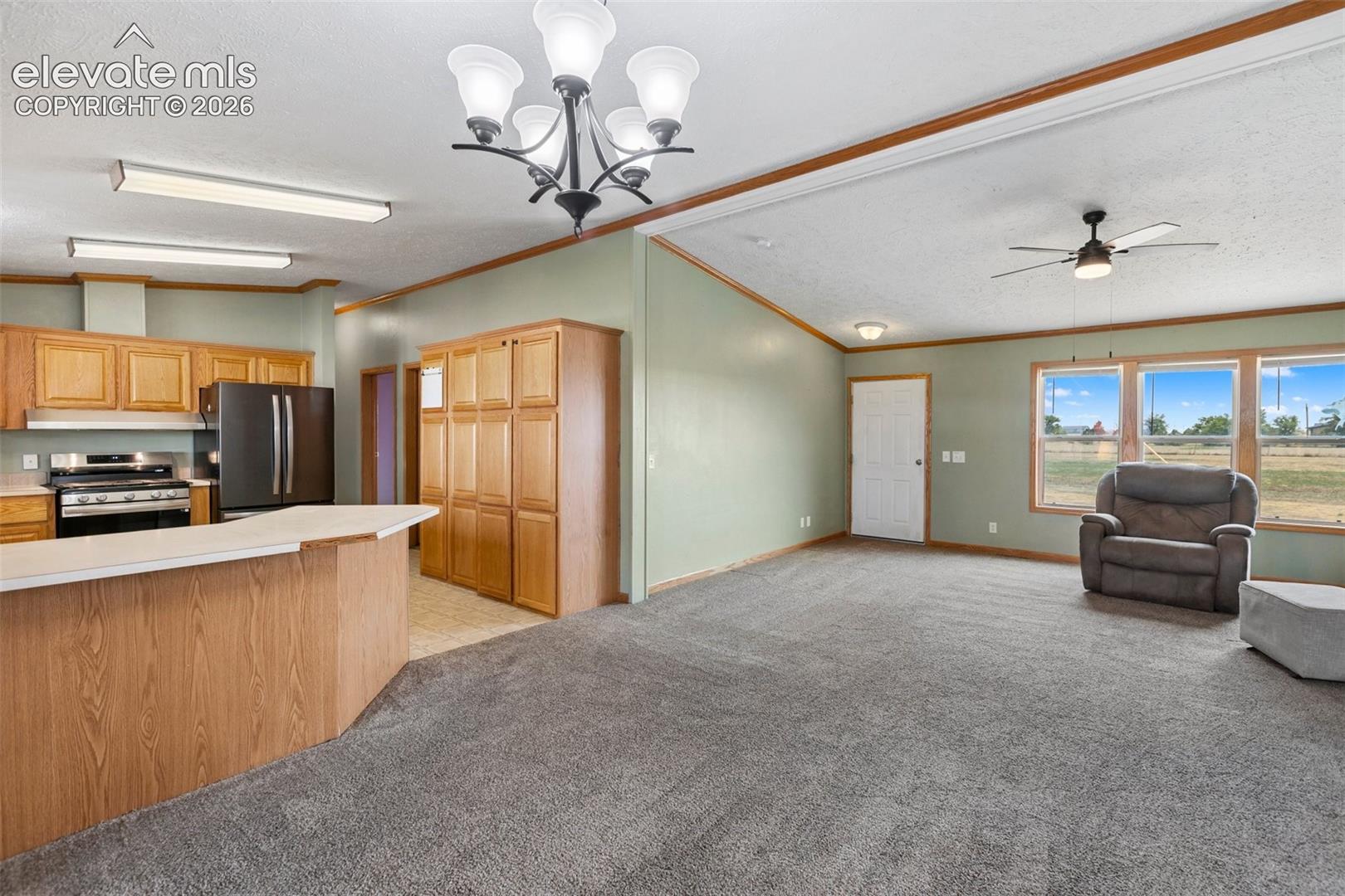 Open-concept living space featuring a kitchen with light wood cabinetry, a breakfast bar, and a full suite of black appliances