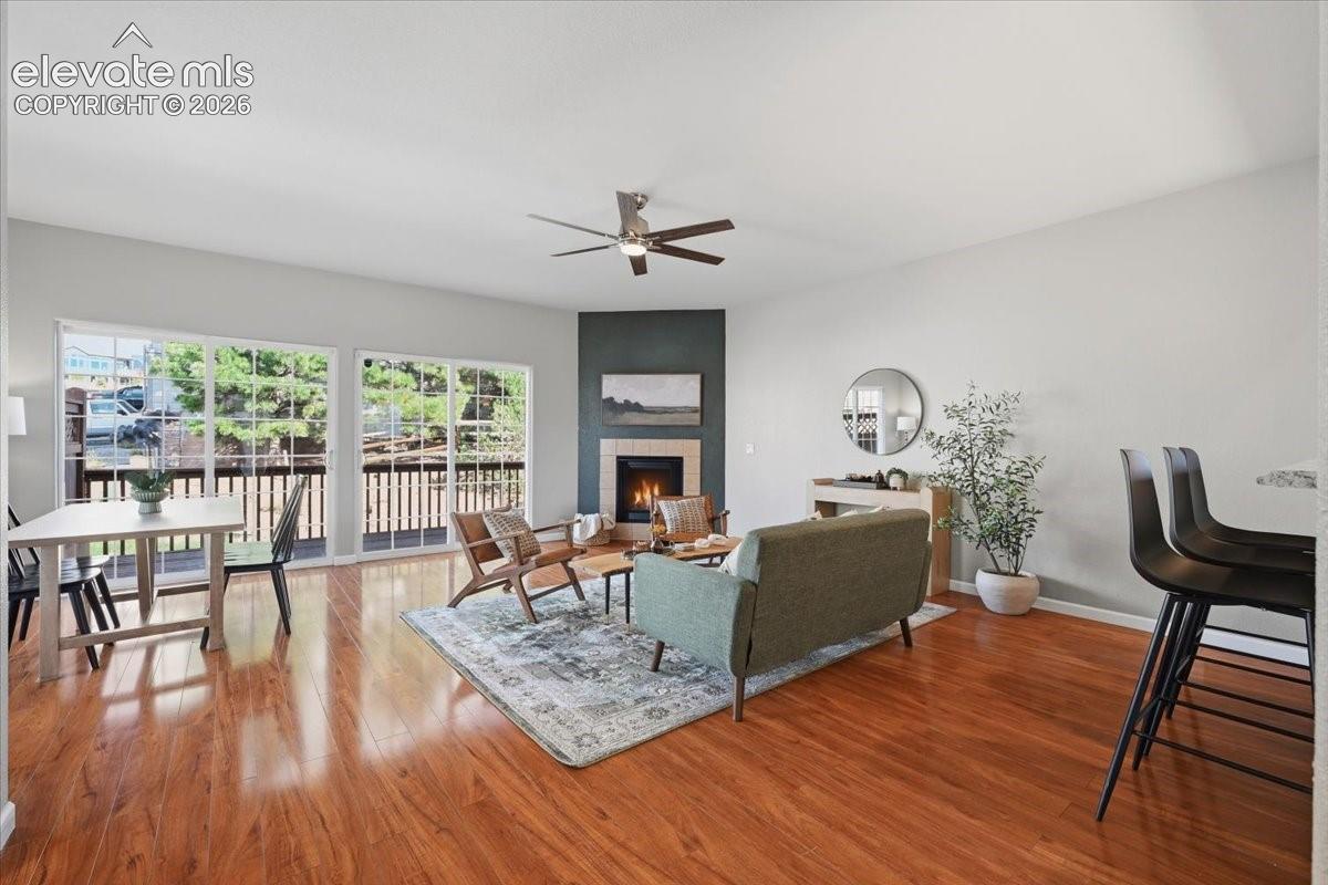 Spacious living area featuring wood flooring, a built-in fireplace with a tile surround, and a ceiling fan