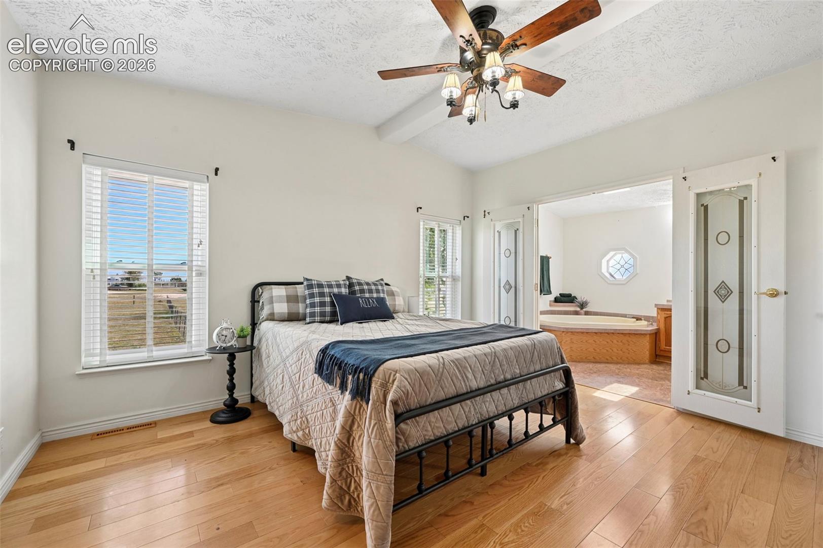 Vaulted ceilings with a ceiling fan, light wood-finish flooring, and French doors featuring decorative glass panels