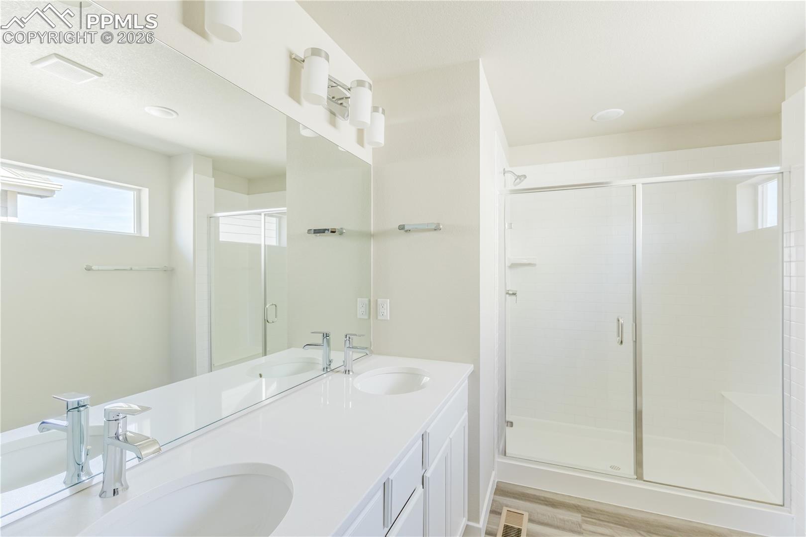 Master Bathroom with double vanity, a shower stall, and light wood finished floors