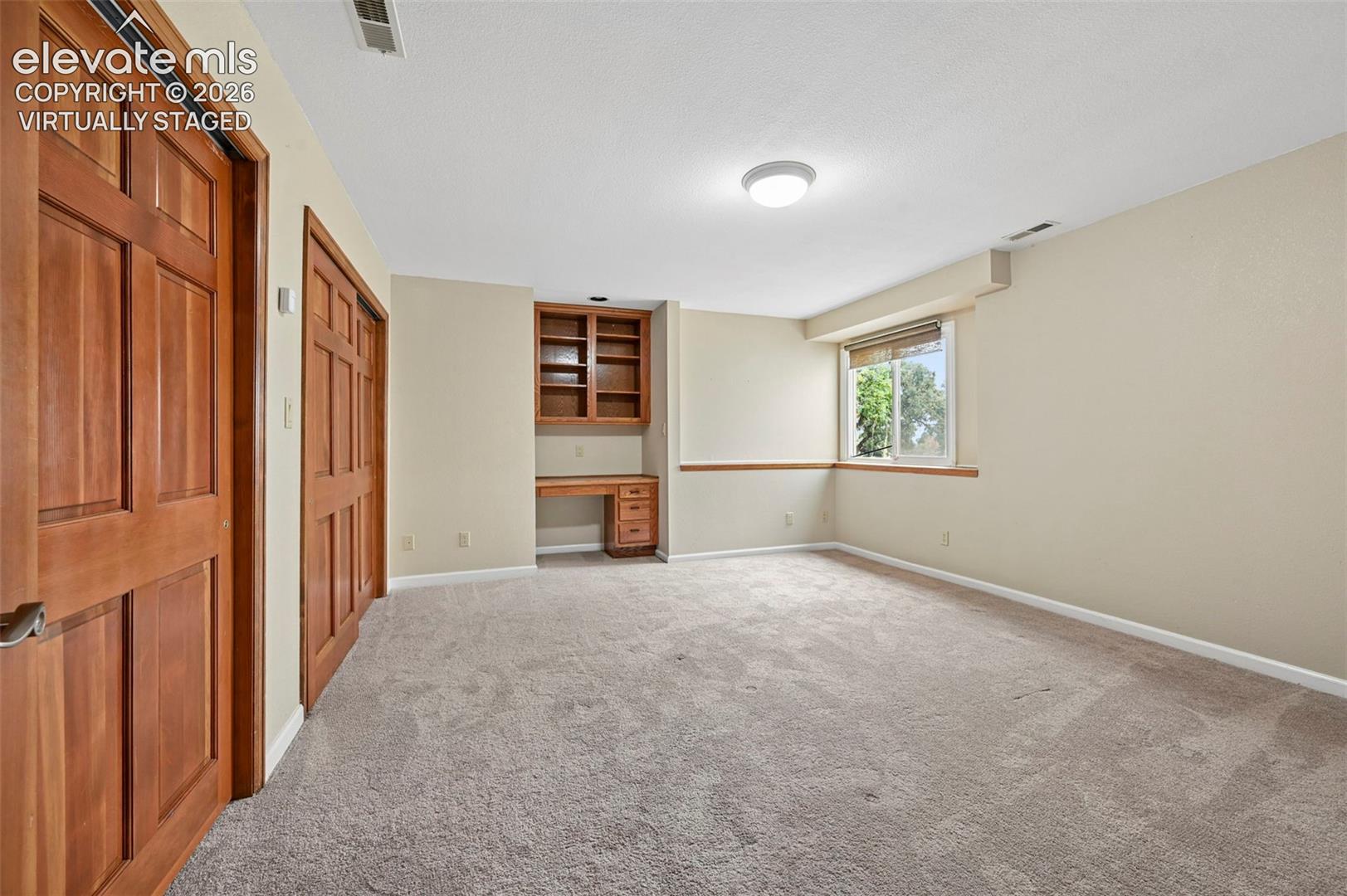 Virtually staged basement bedroom could be used as an office or craft room, as it already has built in shelving and desk!! 