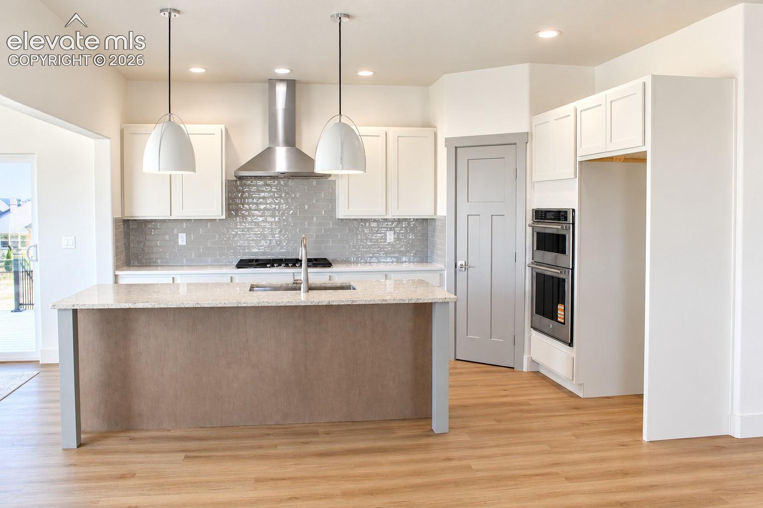 Kitchen featuring a central island with countertop, stainless steel appliances, recessed lighting, wood-finish flooring, and pendant light fixtures