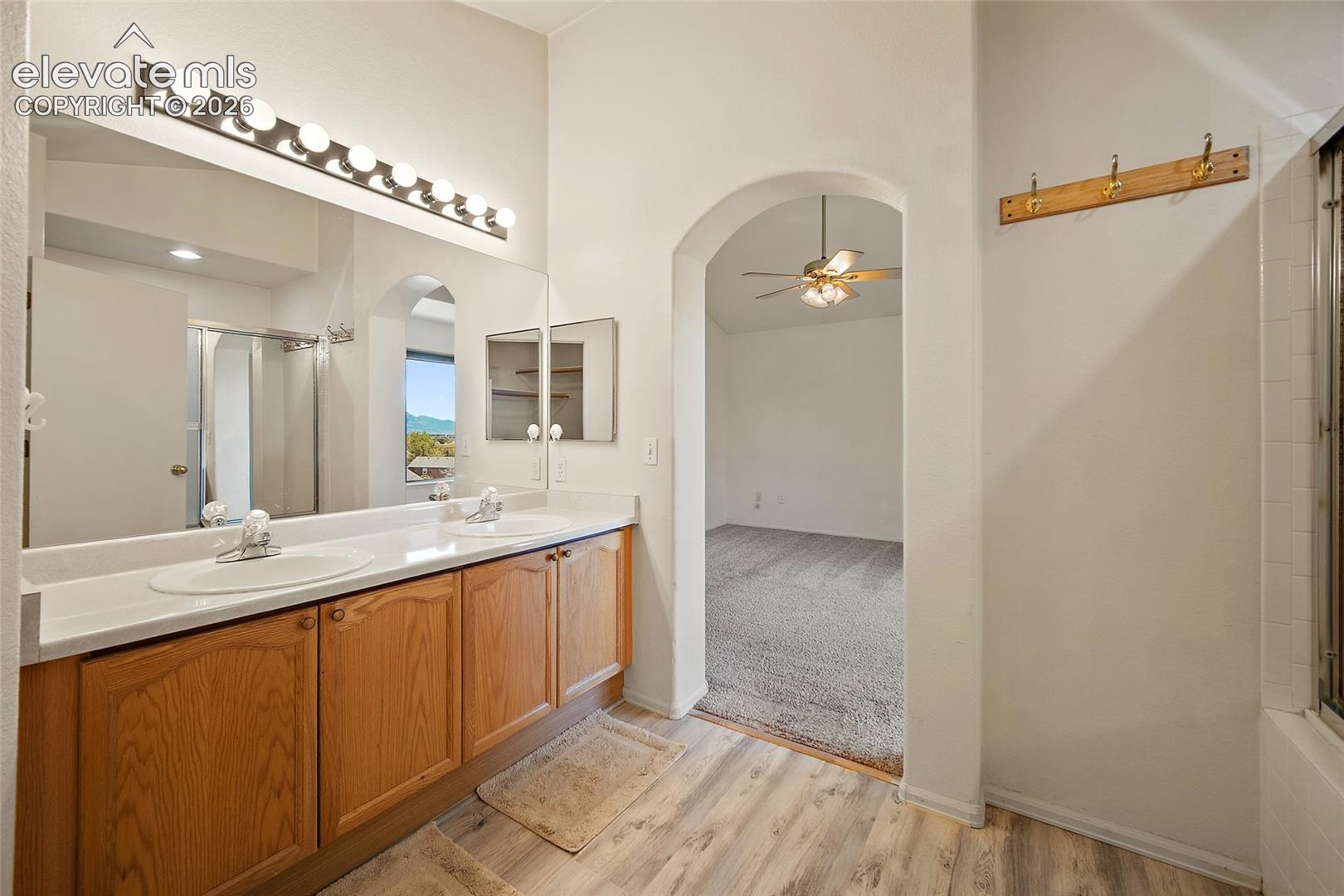 Dual vanity with light wood-finish cabinetry, white countertops, and integrated sinks
