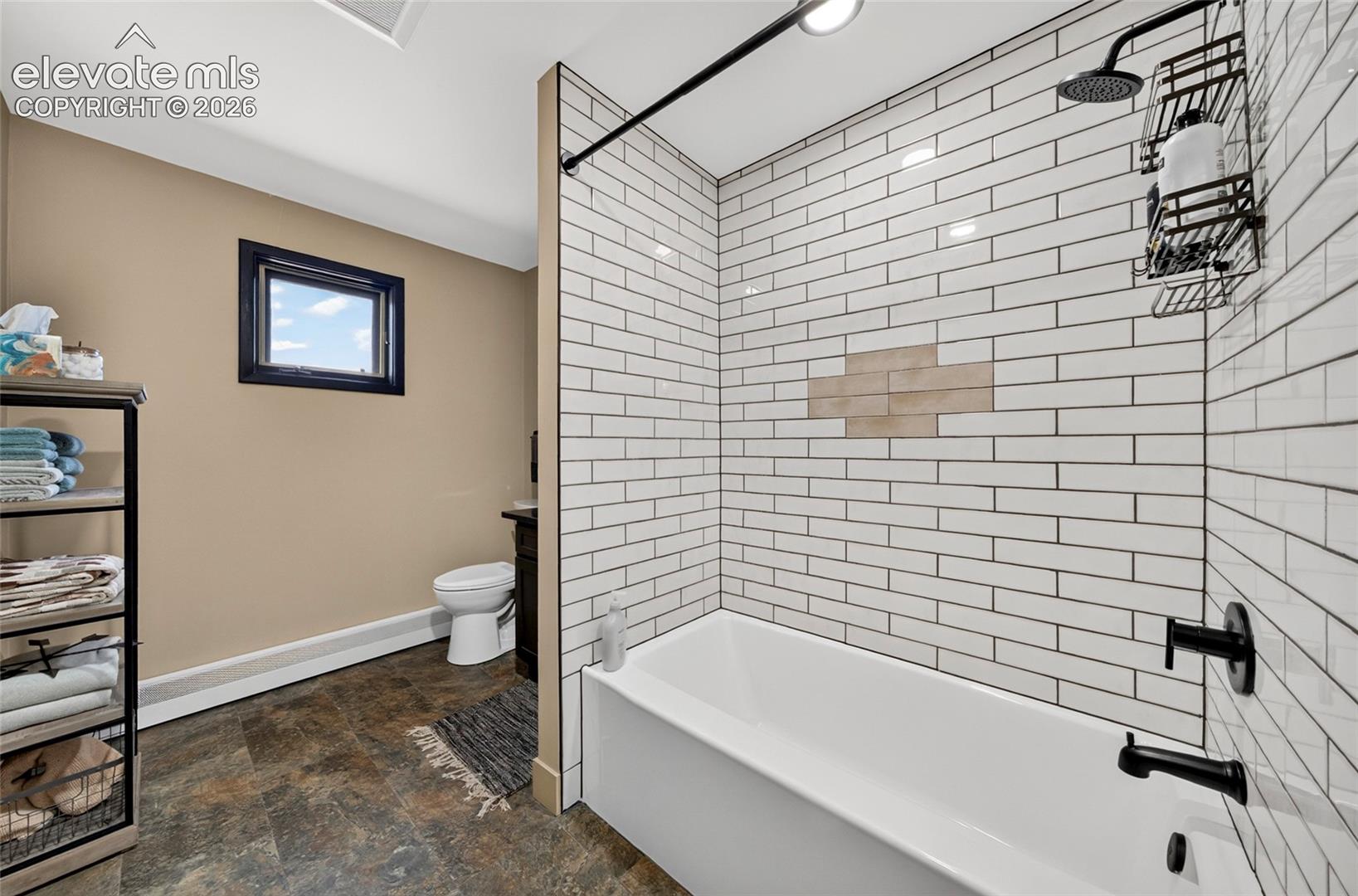 Bathtub with subway tile surround, matte black shower fixtures, and a rain showerhead