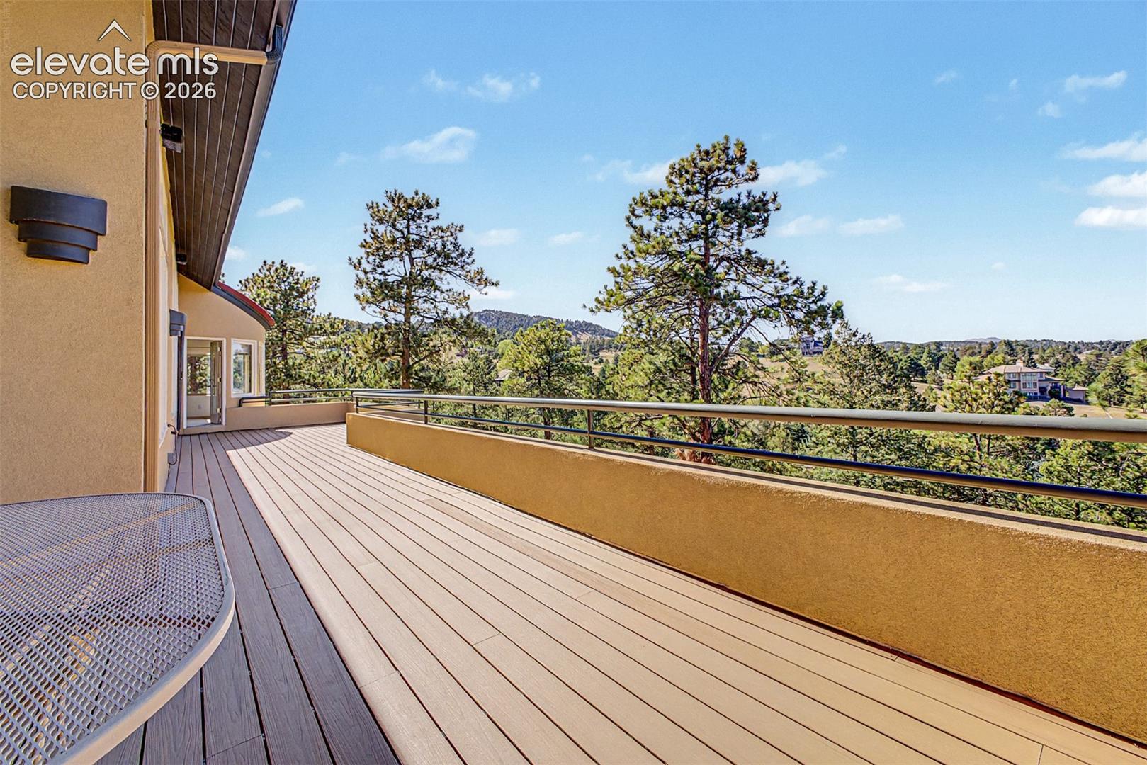 Expansive exterior deck with composite decking, a stucco half-wall, and a metal railing