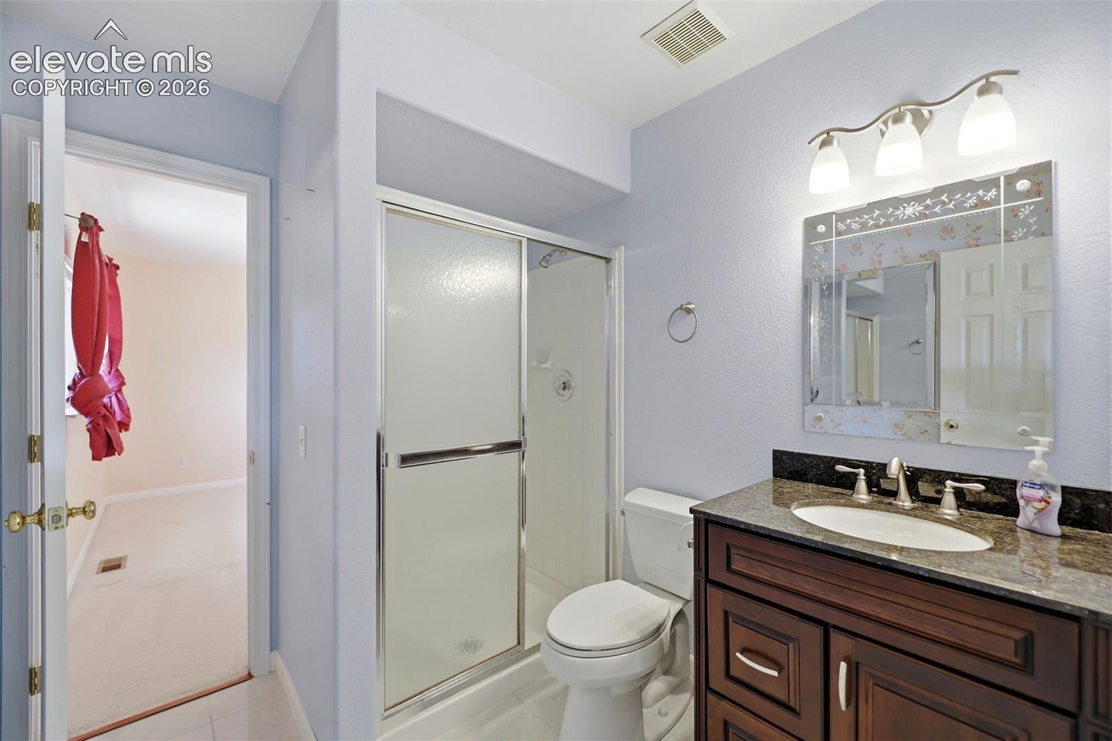 Bathroom featuring a dark wood vanity with a granite countertop, undermount sink, and a decorative framed mirror