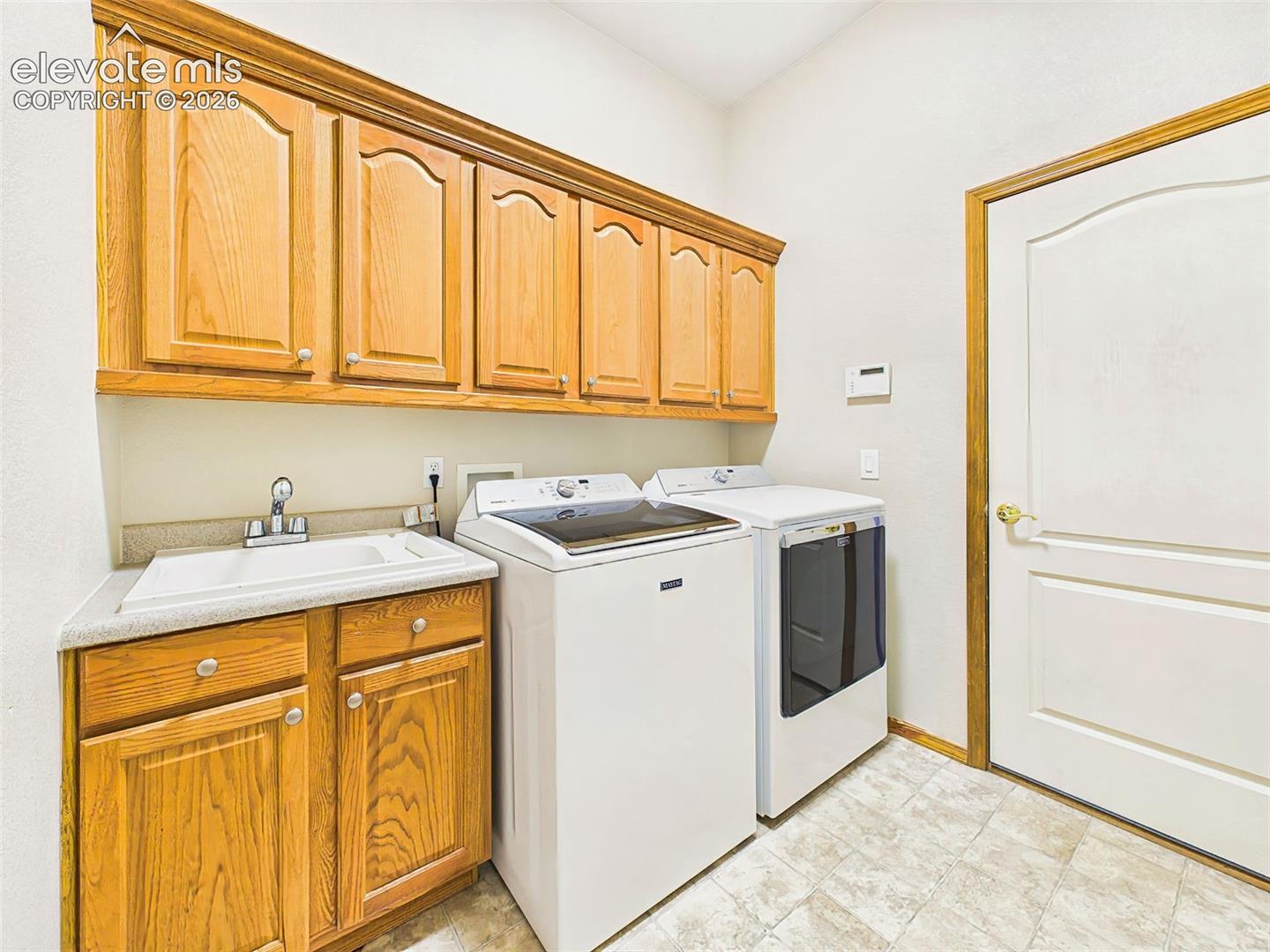 Dedicated laundry room with built-in cabinetry, utility sink, and additional storage space walks out to garage