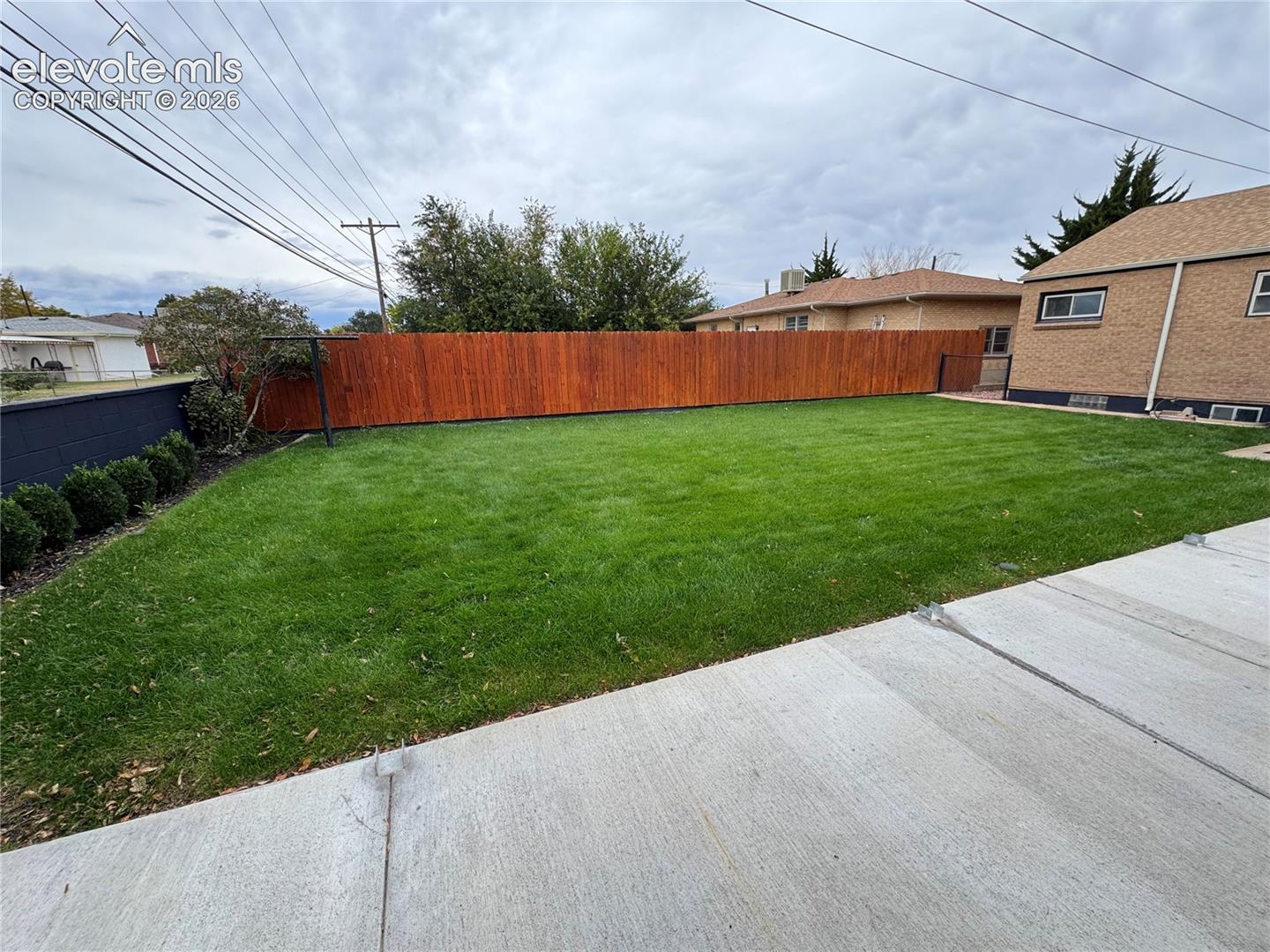 Backyard featuring a manicured lawn, concrete patio, and a full-height wood-slat privacy fence