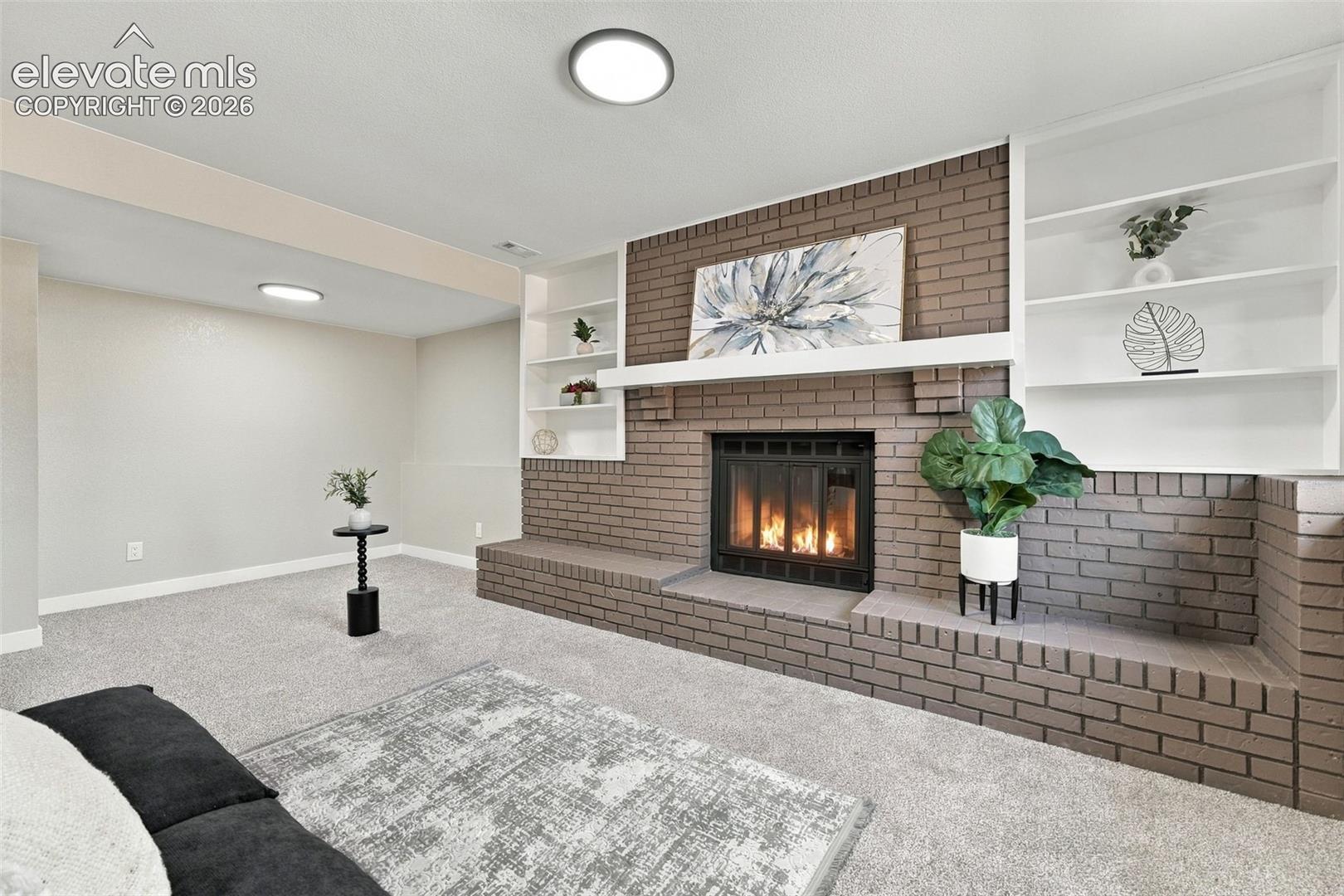Brick fireplace featuring an extended hearth, integrated shelving, and a horizontal mantel