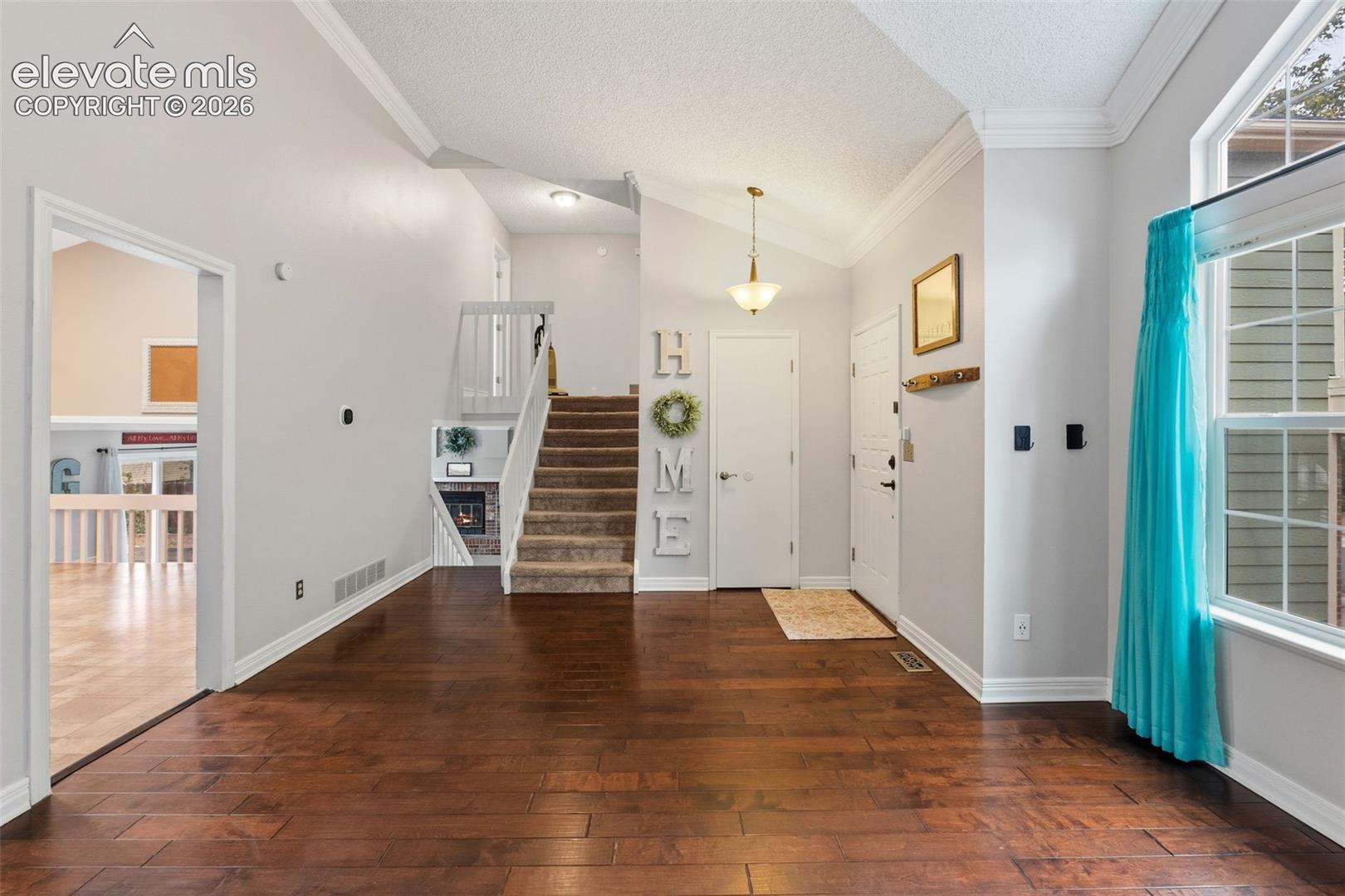Wood-finish flooring throughout, vaulted ceiling, and an integrated staircase with a recessed fireplace
