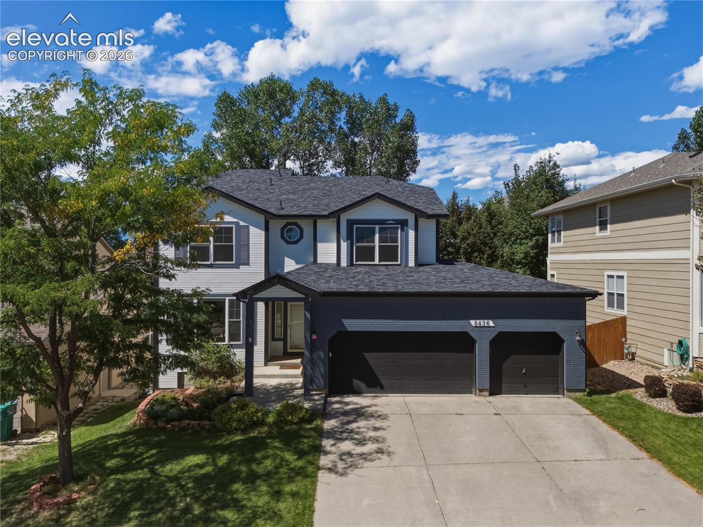 Two-story residence with a two-car garage, concrete driveway, and front yard landscaping