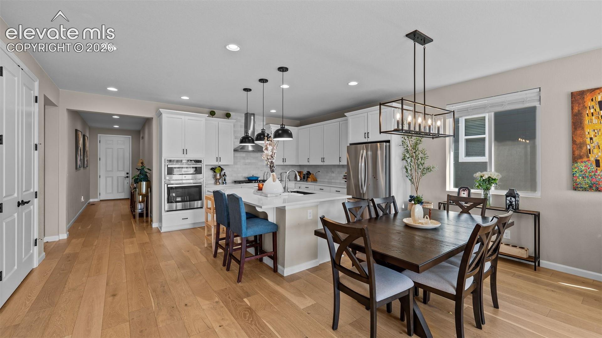 Gourmet kitchen featuring white cabinetry, stainless steel appliances, and a central island with countertop seating