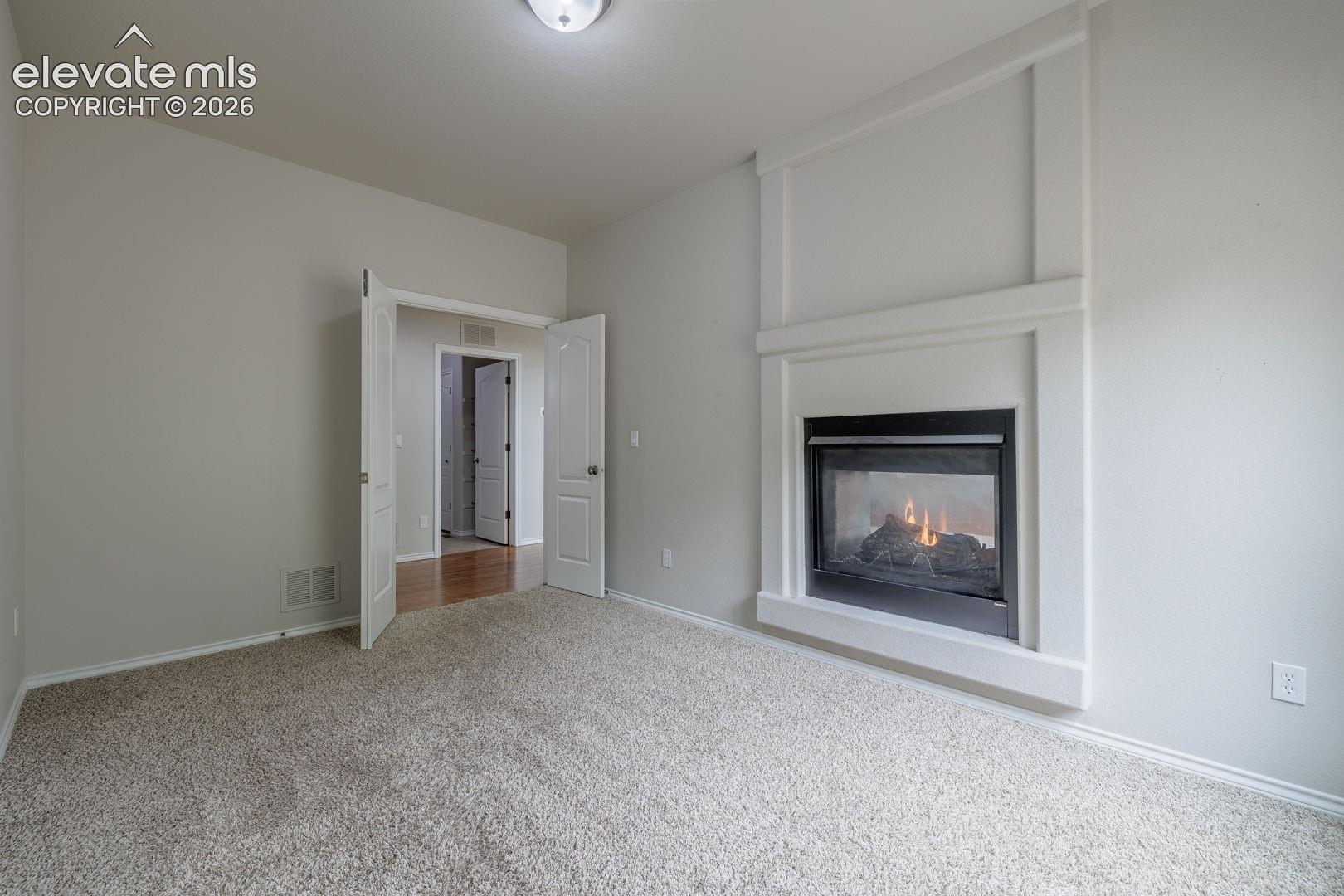 Room featuring a white-trimmed fireplace with a dark insert, neutral-toned carpeting, and light-colored walls