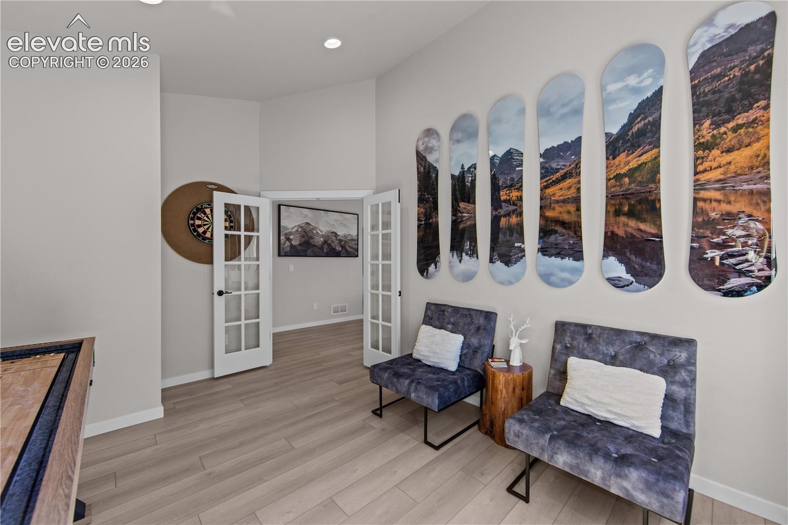 Vaulted ceilings, wood-finish flooring, and white-framed French doors with glass panes
