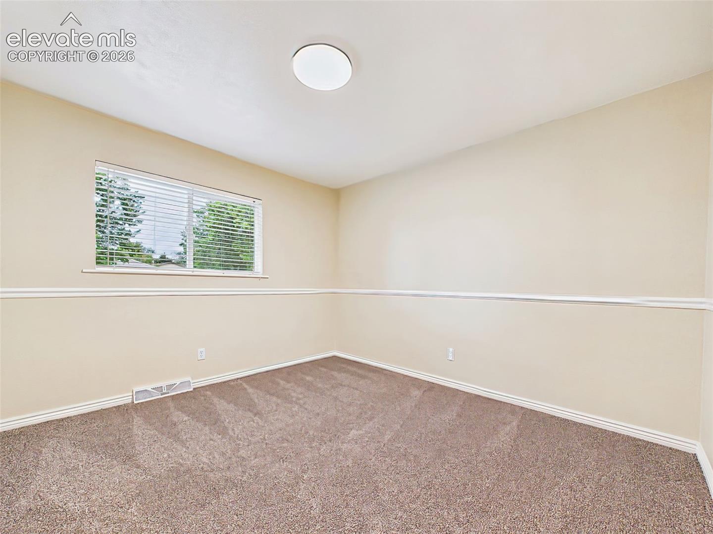Spacious secondary bedroom featuring brand-new carpet, a large picture window, and neutral finishes ready to suit a variety of needs.
