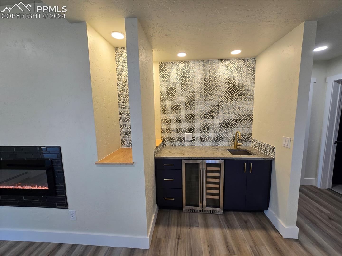 Bar with a textured ceiling, backsplash, wine cooler, sink, and dark hardwood / wood-style floors