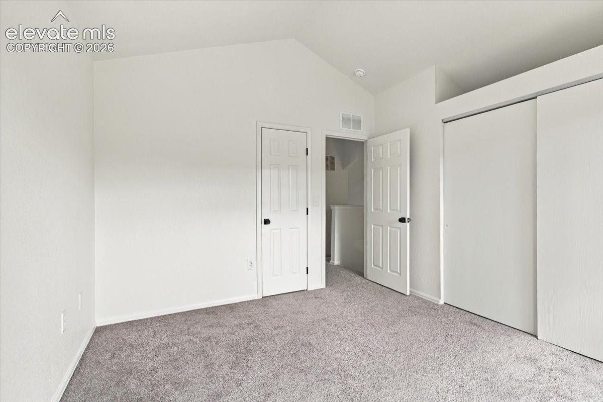 Room featuring vaulted ceilings, neutral carpeting, and a dual-panel sliding closet