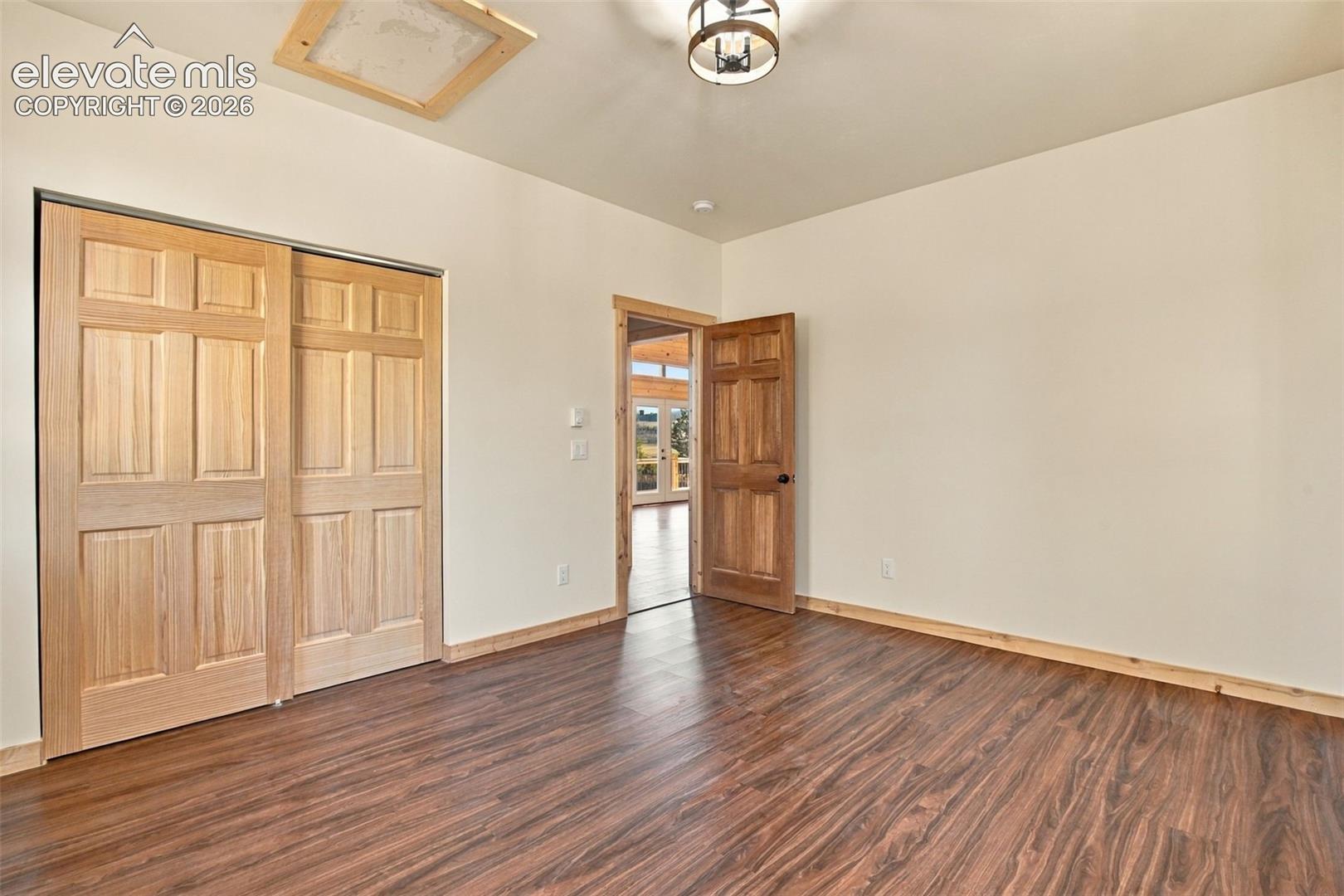 Wood-finish flooring, natural wood interior doors, wood-frame closet doors, and a rustic-style chandelier