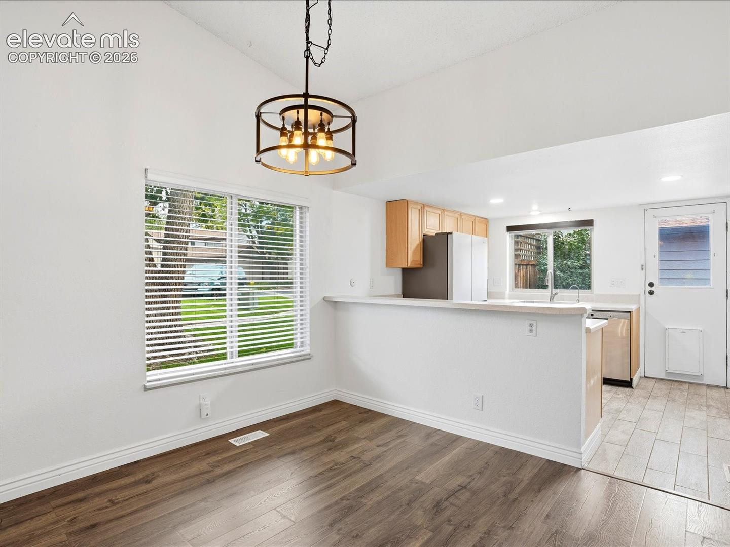 Wood-finish flooring throughout, drum-style chandelier, breakfast bar, and tile flooring in the kitchen area