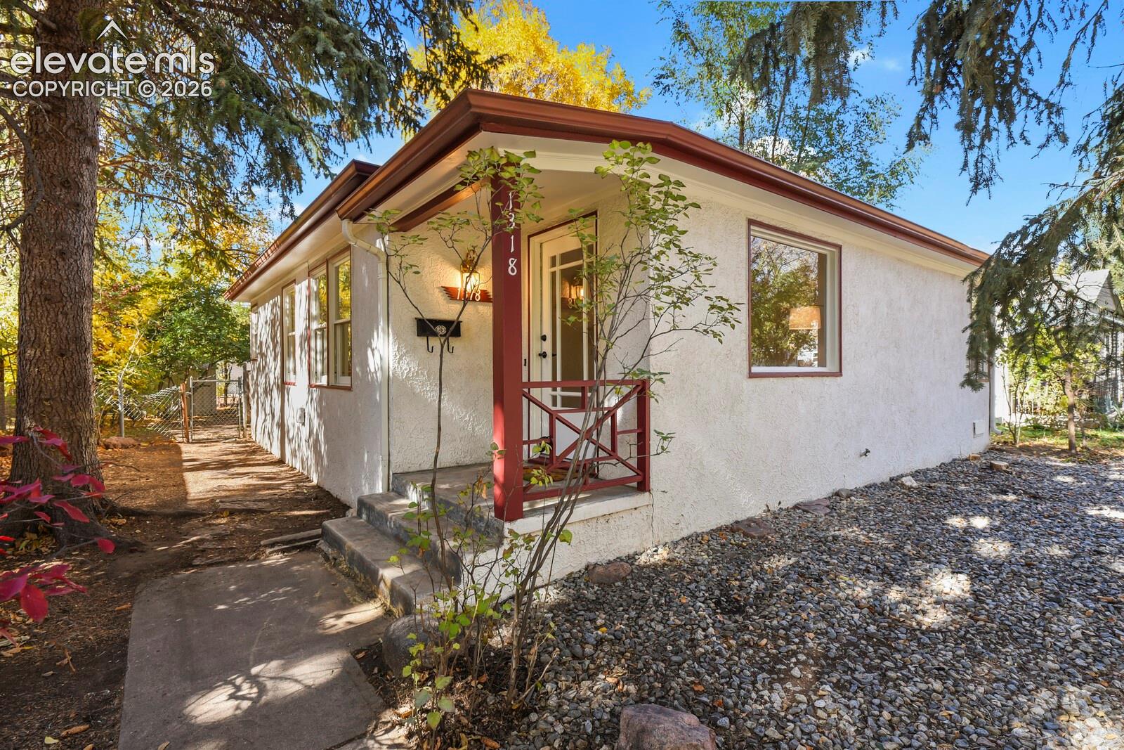 Stucco exterior with contrasting trim, covered entryway, decorative front railing, and large windows