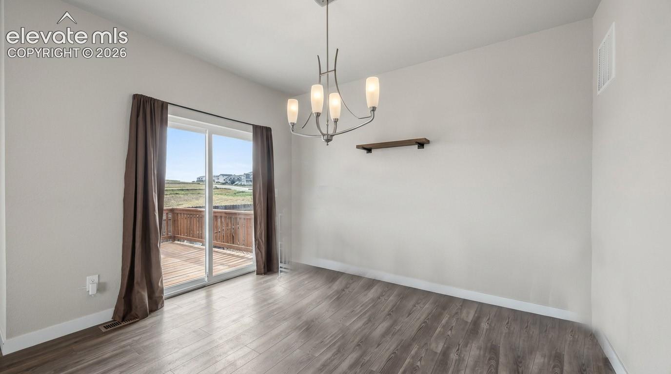 The Dining Area has a modern light fixture and slider out to an expansive backyard wood deck.