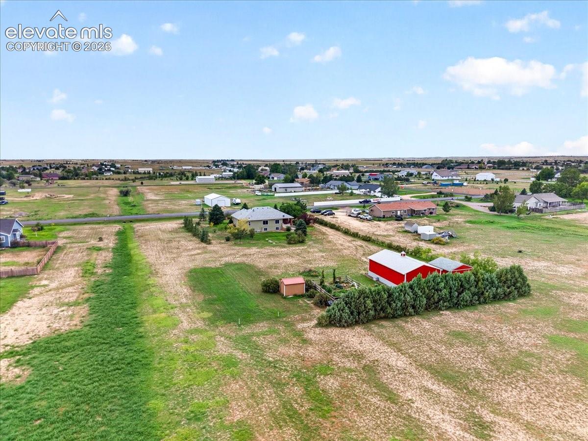 Expansive acreage featuring a red metal-sided outbuilding, mature evergreen hedging, and an additional storage structure