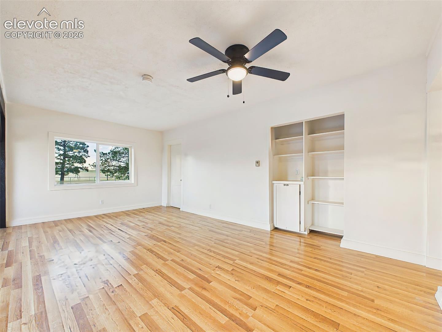 Living Room – Comfortable living area with built-in shelving, oversized windows, and plenty of room for relaxing or entertaining.
