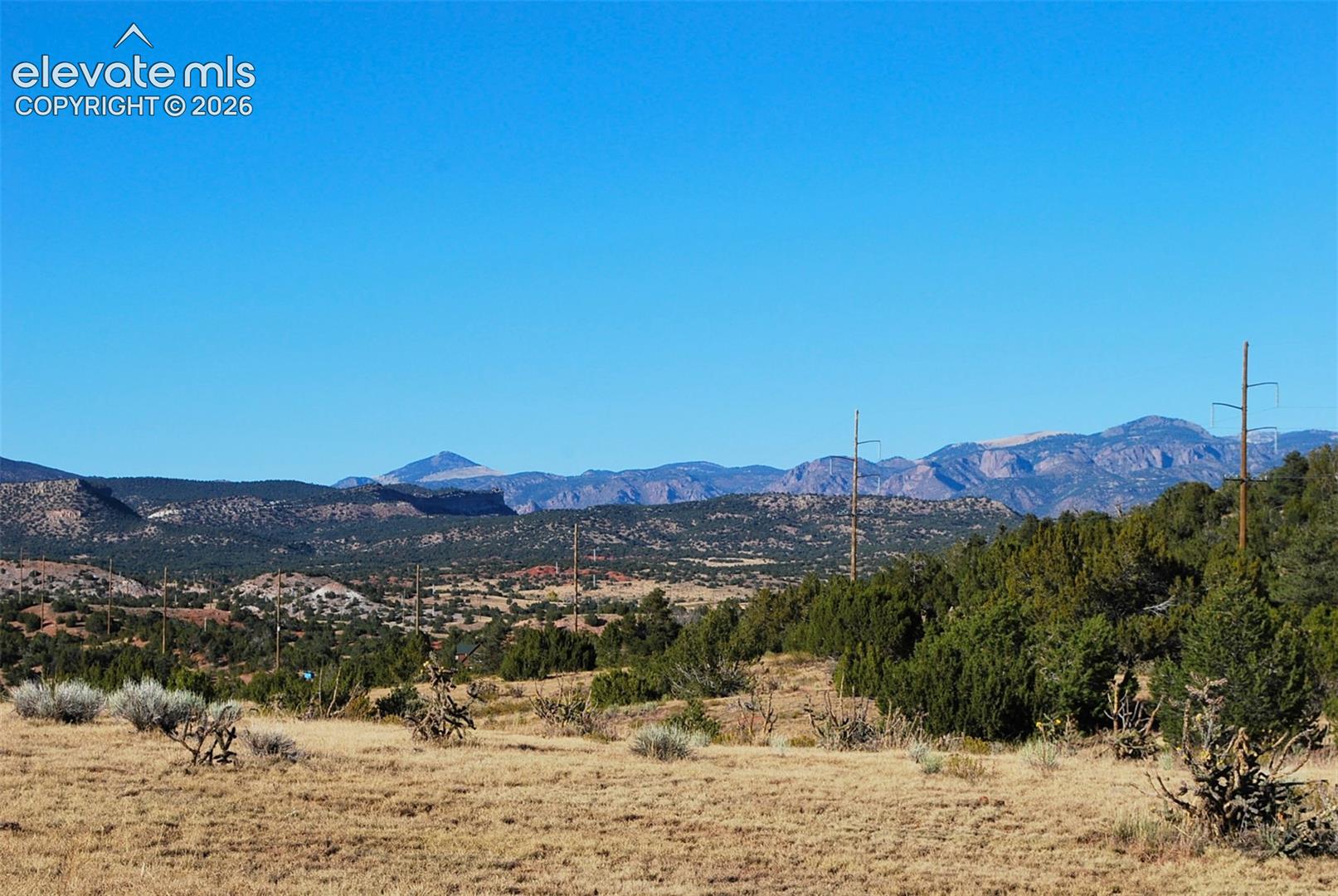 Expansive terrain with distant mountains, clear blue sky, and natural vegetation