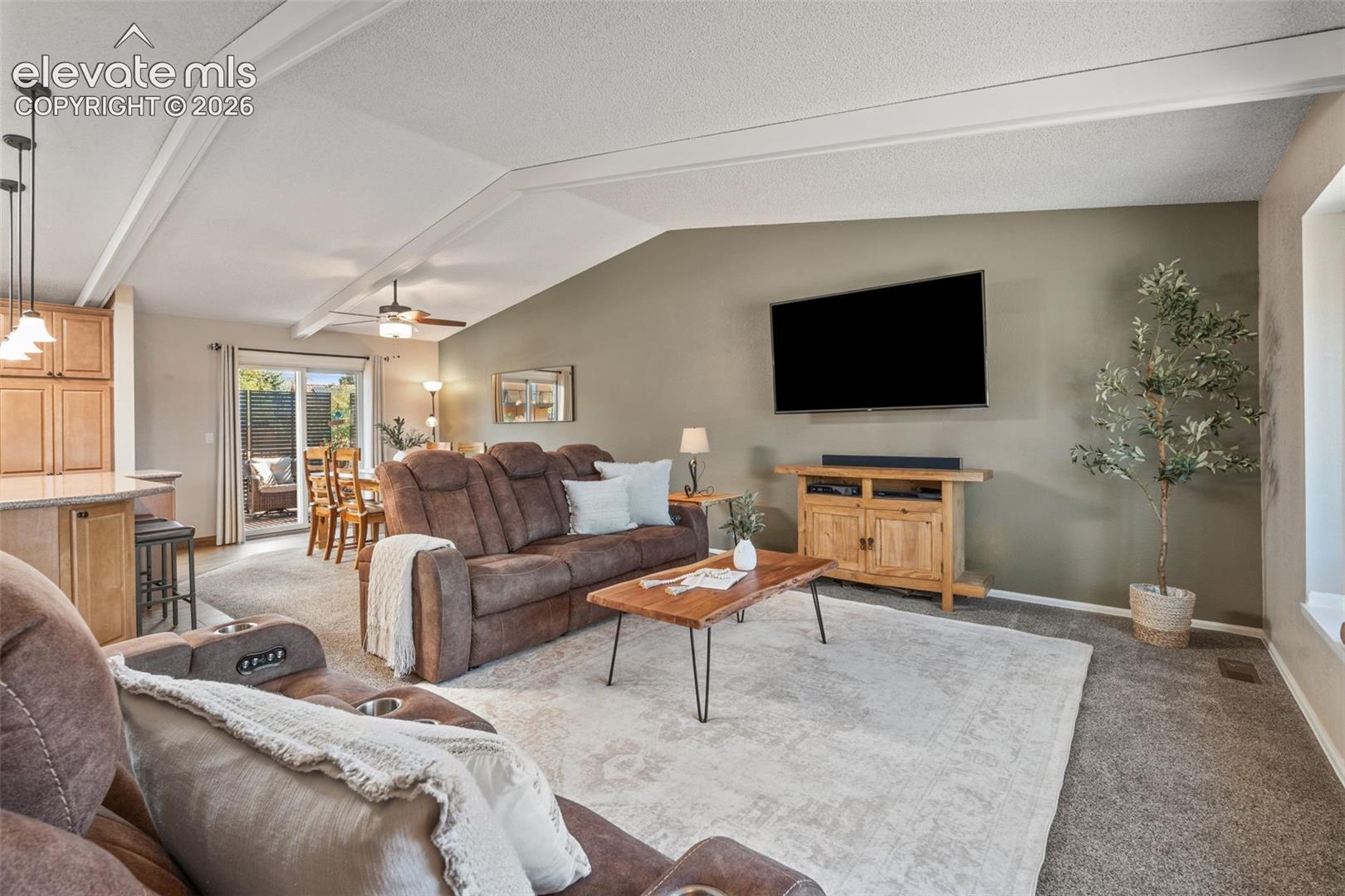 Vaulted ceilings, sliding glass door, recessed lighting, and kitchen island with light-toned cabinetry