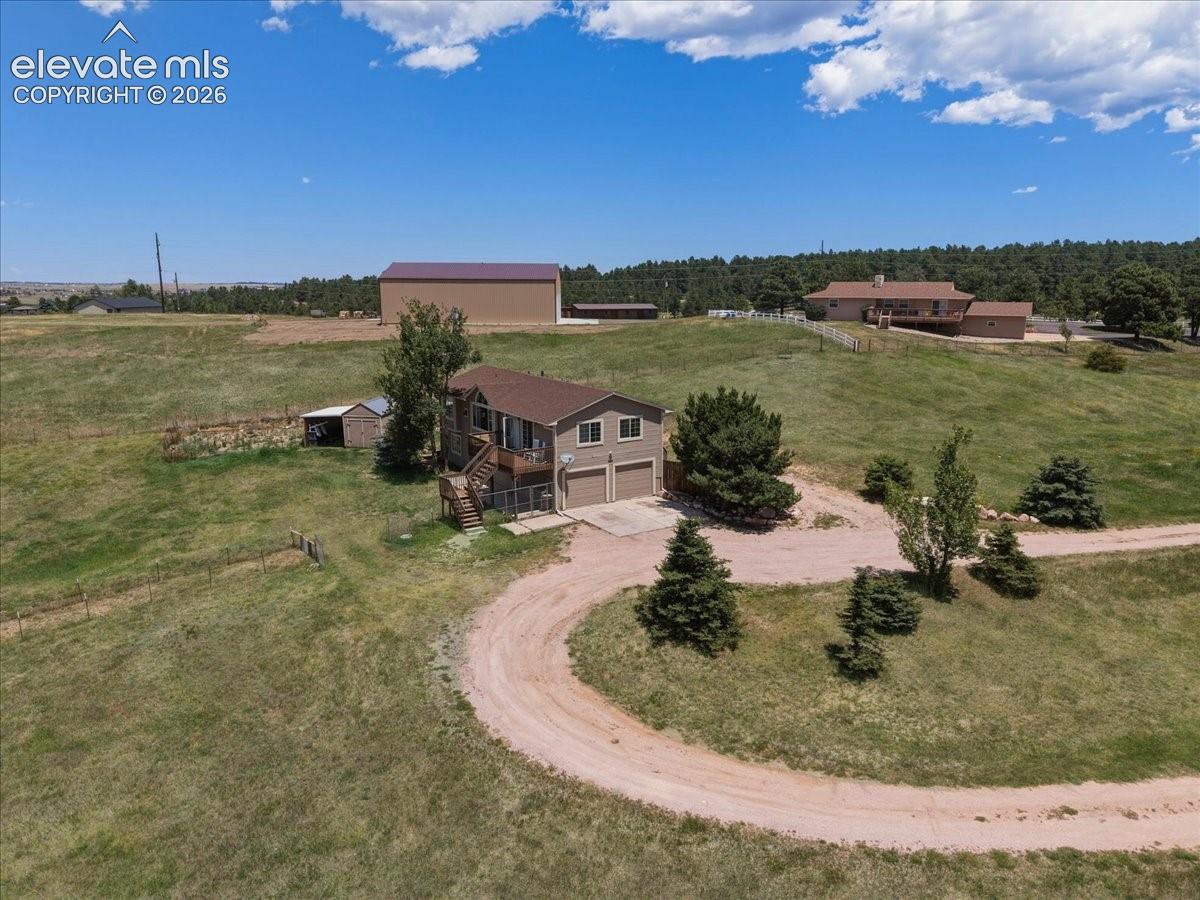 Multi-level residence featuring an attached two-car garage, expansive exterior wood decking, and a separate large-scale detached outbuilding on a spacious acreage lot
