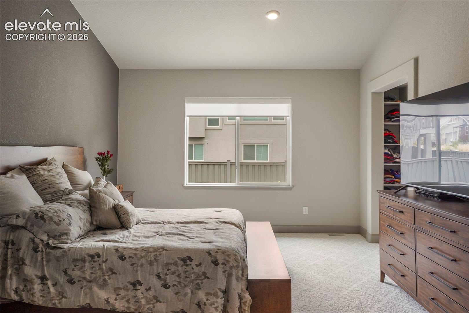 Carpeted room with a textured accent wall, recessed lighting, and a double-pane window