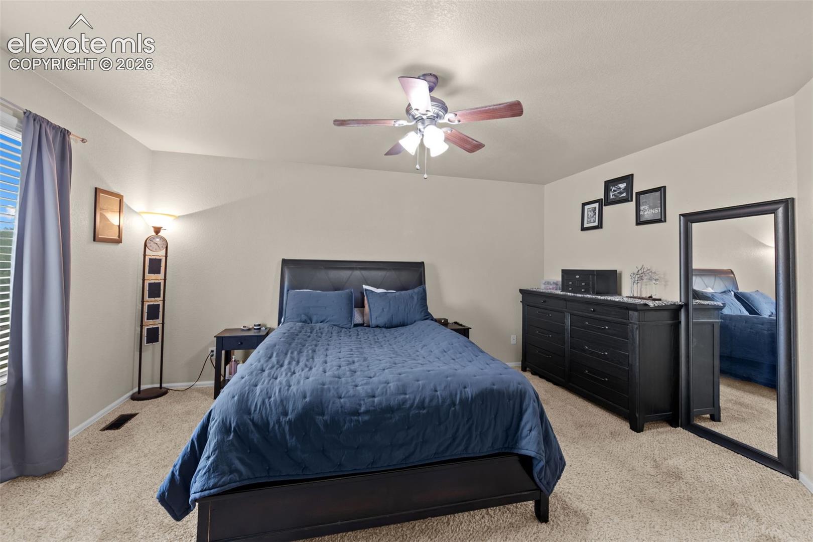 Recessed window with blinds, ceiling fan with integrated lighting, carpeted flooring, and neutral wall paint