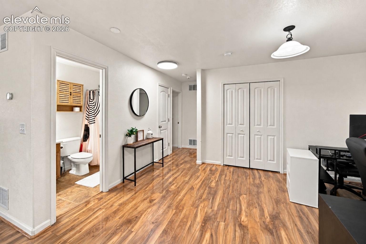 Wood-finish flooring throughout, white walls, and a recessed ceiling light
