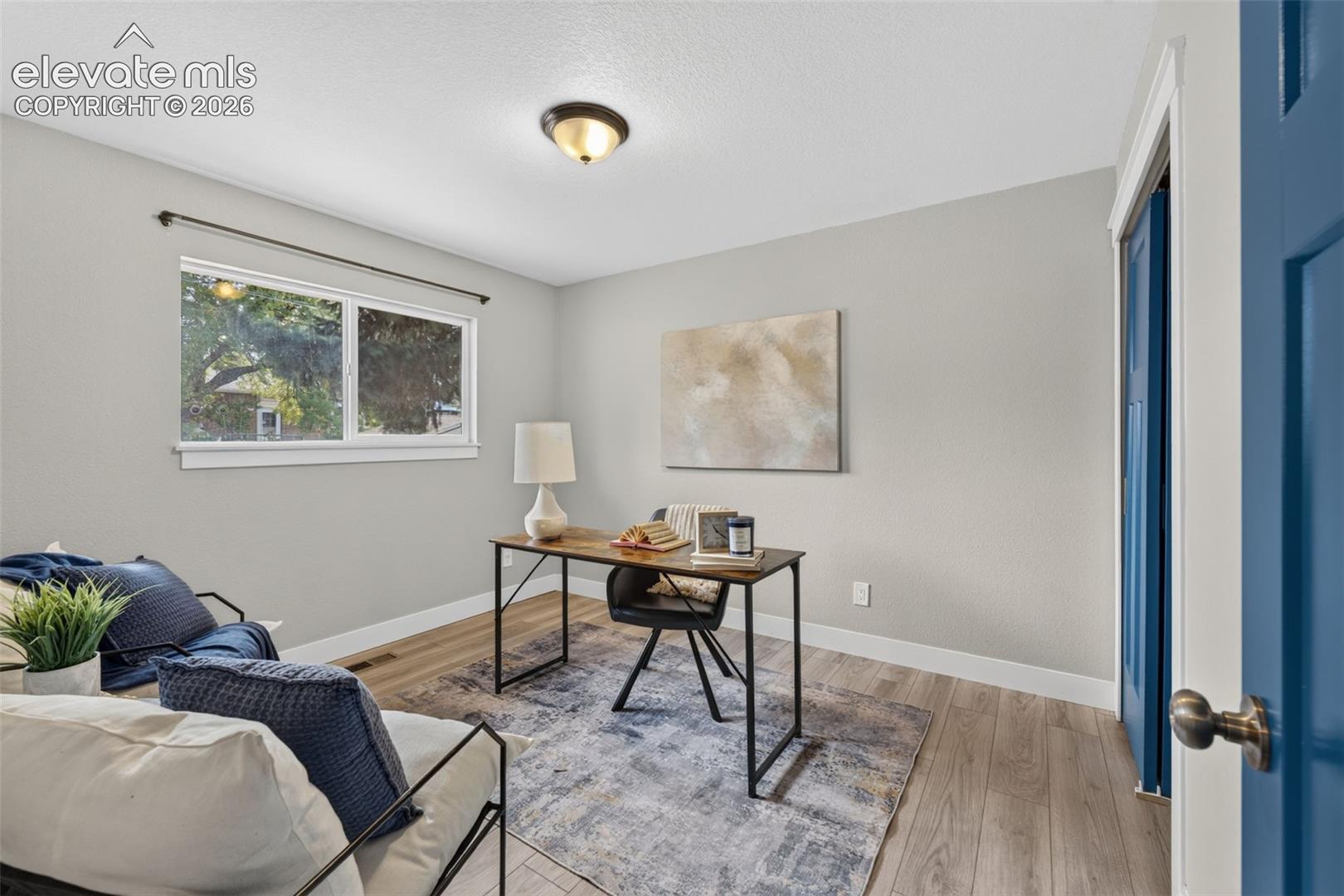 Neutral-toned interior featuring wood-finish flooring, a horizontal sliding window, and a paneled door with metallic hardware