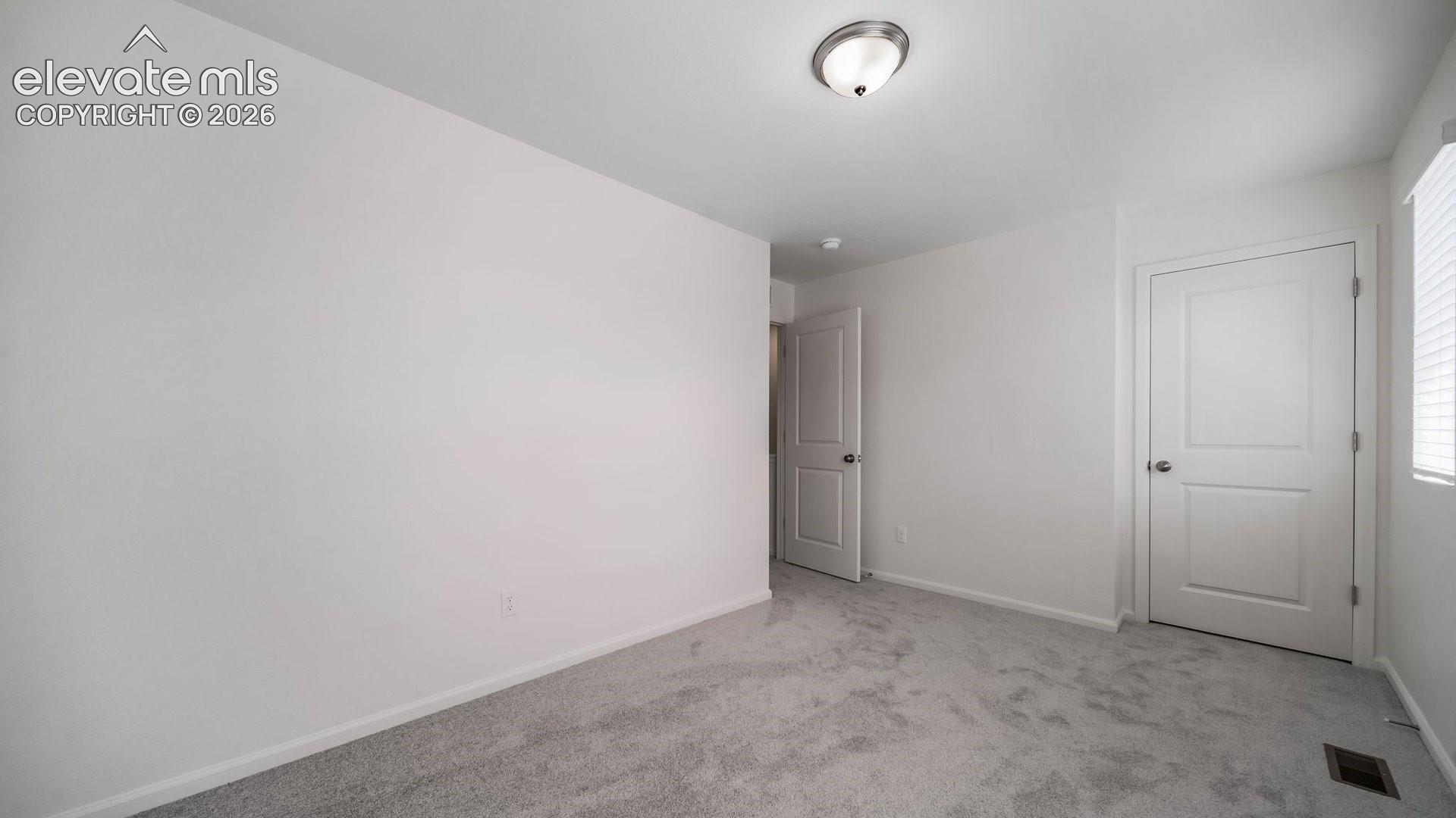 Neutral-toned wall-to-wall carpeting, crisp white walls, two-panel interior doors with brushed nickel hardware, and a dome-style ceiling light fixture
*photos of a model home*