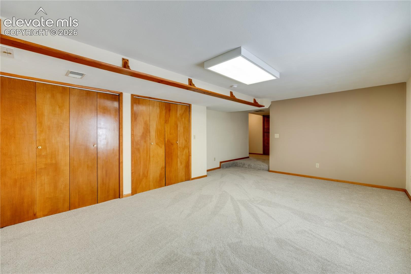 Large basement family room with closets, under the stairs storage area with shelves