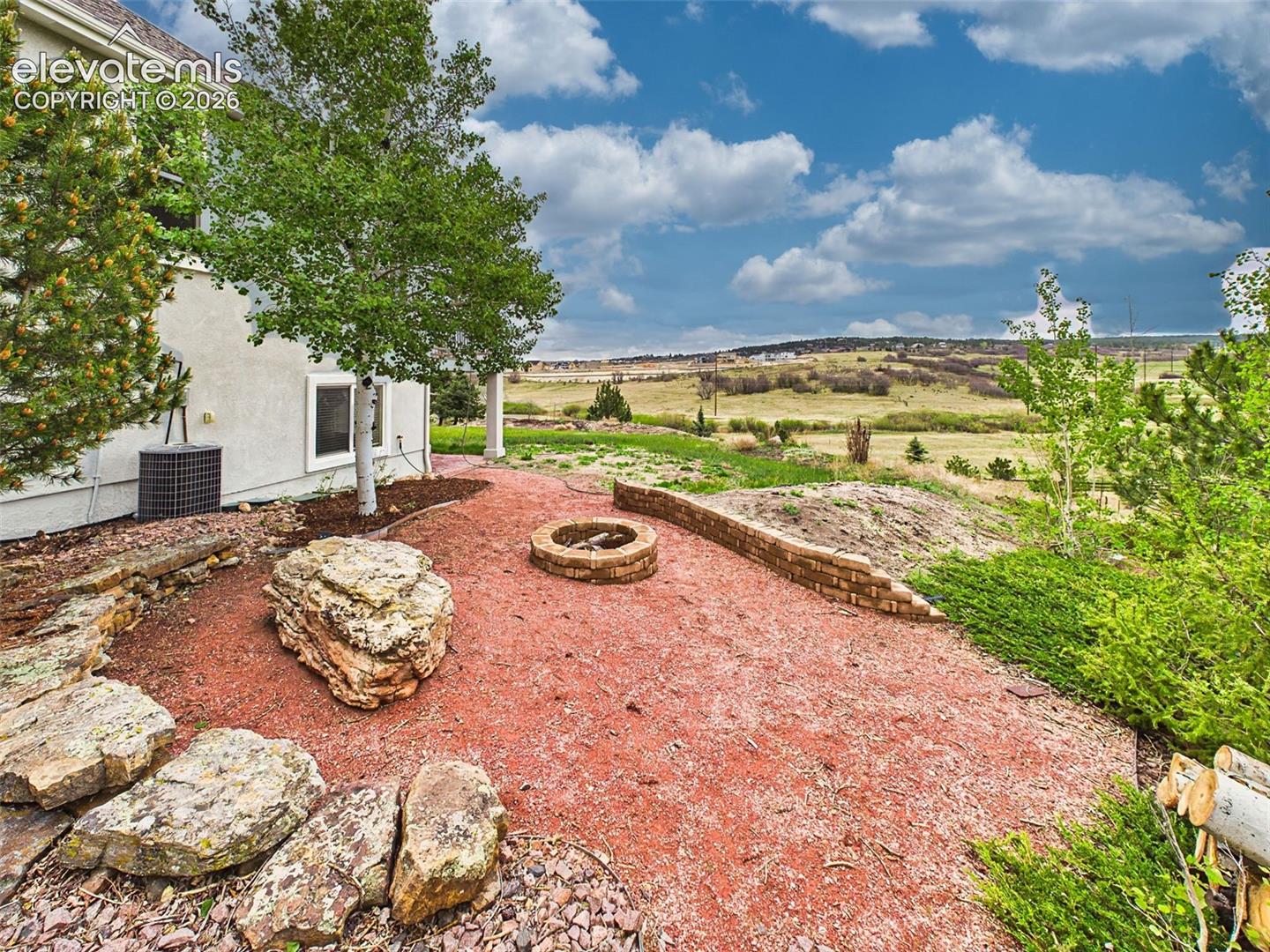 Landscaped outdoor retreat featuring a built-in fire pit area and scenic open-space backdrop.