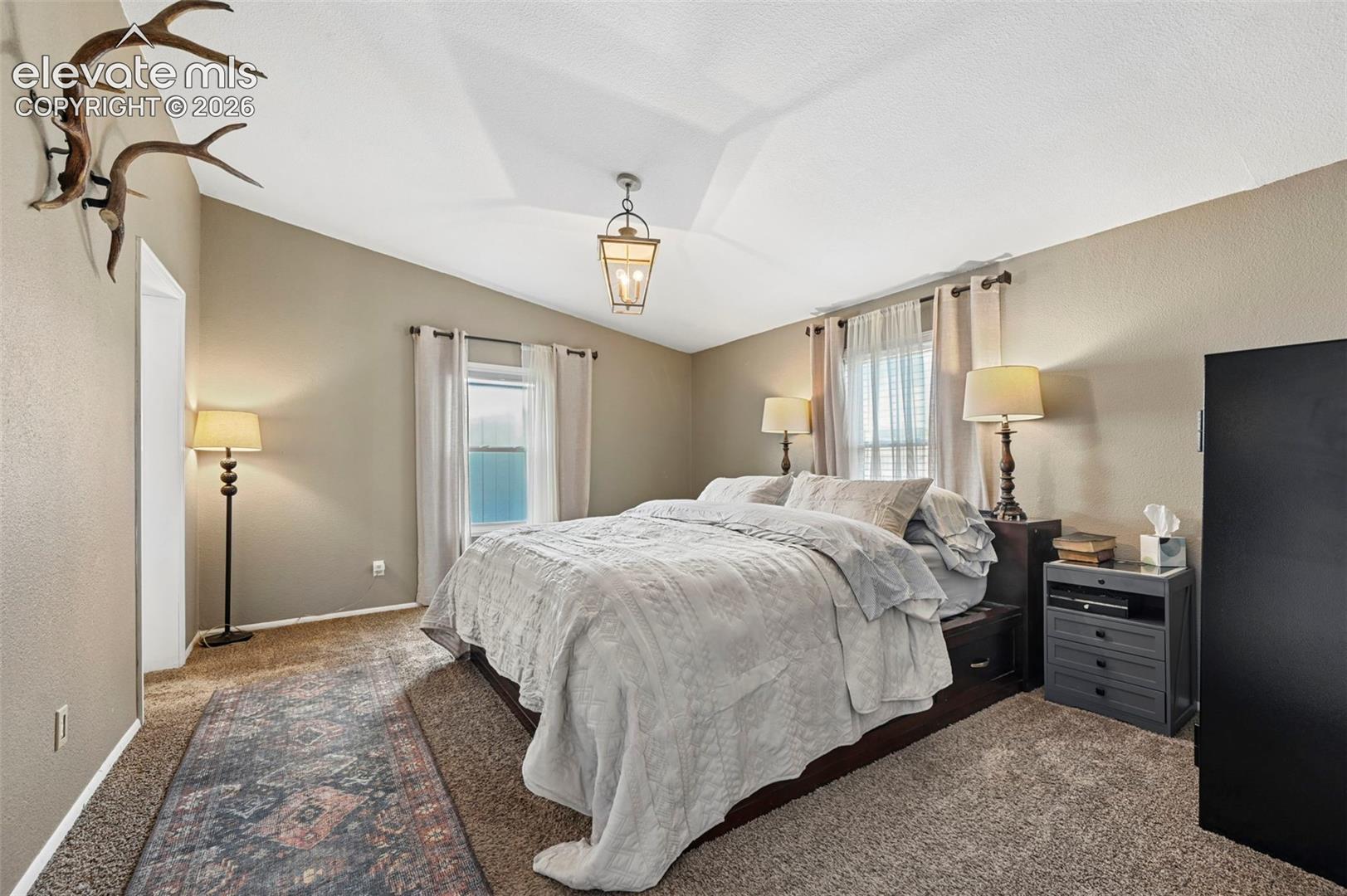 Vaulted ceiling featuring a central lantern-style pendant light and multiple windows