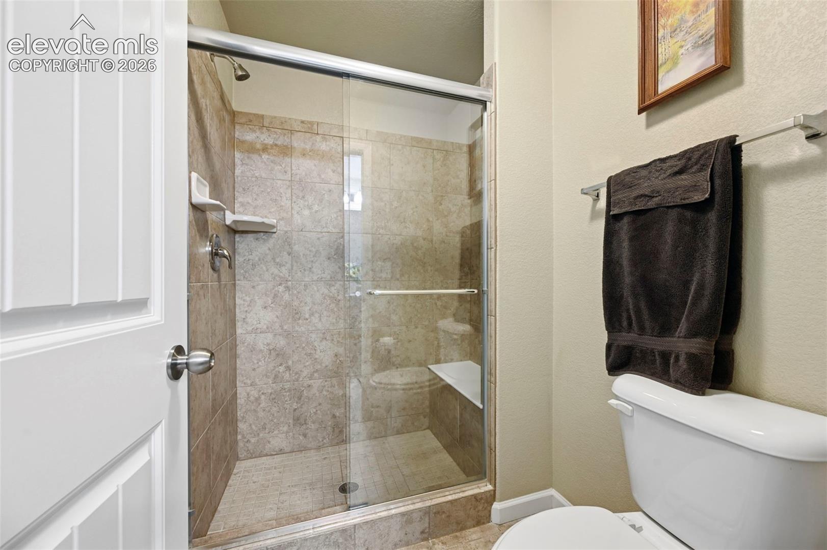 Shower enclosure featuring a built-in bench, tiled walls, and a glass sliding door