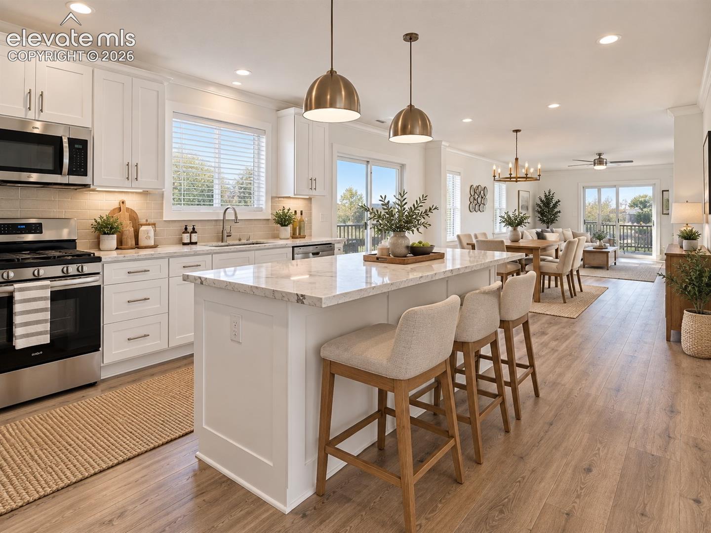 Kitchen & Dining Area – Generous center island provides ample prep space and seating, complemented by white cabinetry, stainless steel appliances, recessed lighting, and an adjacent dining area.