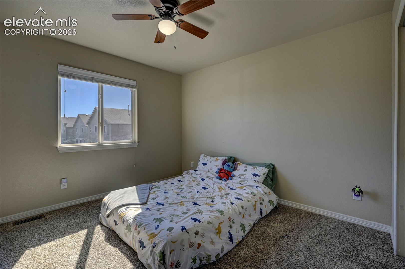 Carpeted room featuring a window with white trim, a ceiling fan with integrated lighting, and neutral wall tones