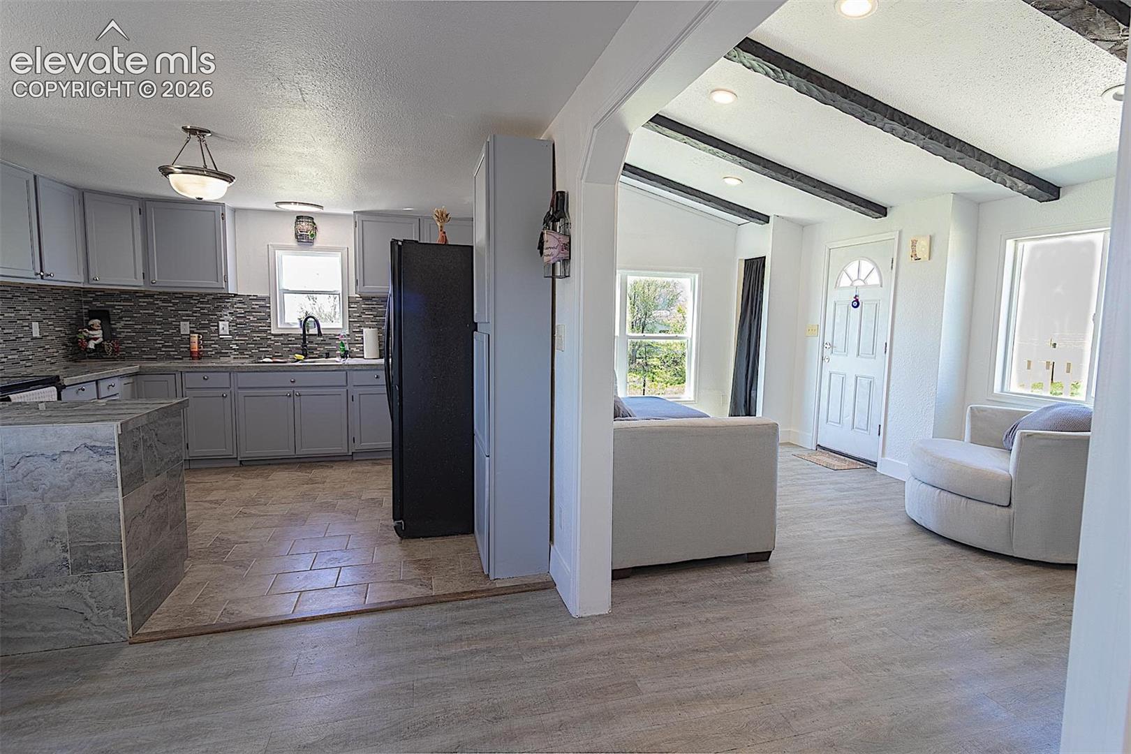 Kitchen with freestanding refrigerator, healthy amount of natural light, backsplash, gray cabinets, and a textured ceiling